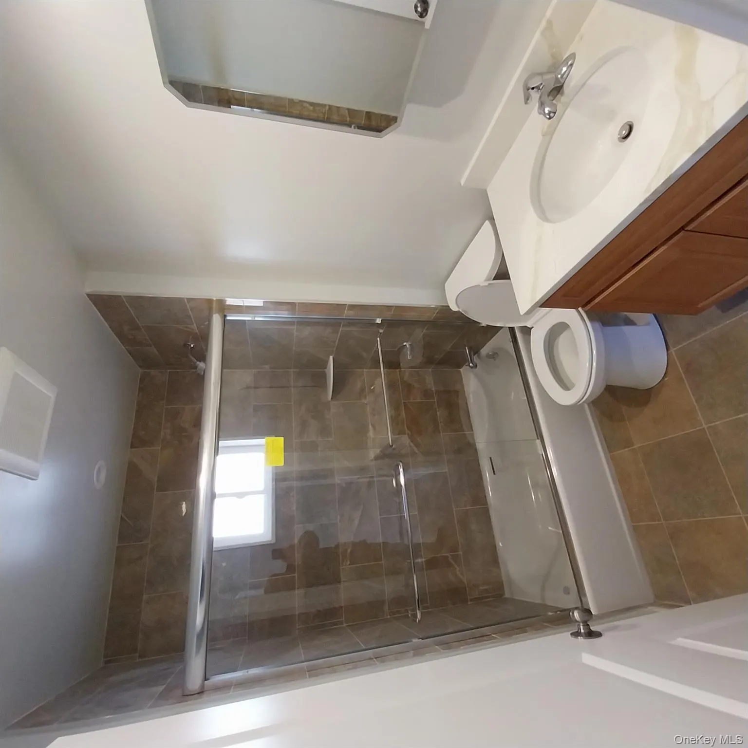 Bathroom with bath / shower combo with glass door, vanity, and dark tile patterned floors Bathroom with bath / shower combo with glass door, vanity, and dark tile patterned floors