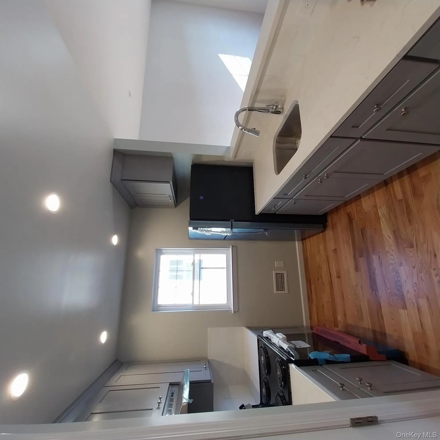 Kitchen featuring gray cabinetry, range, freestanding refrigerator, light wood-style flooring, and light stone countertops Kitchen featuring gray cabinetry, range, freestanding refrigerator, light wood-style flooring, and light stone countertops