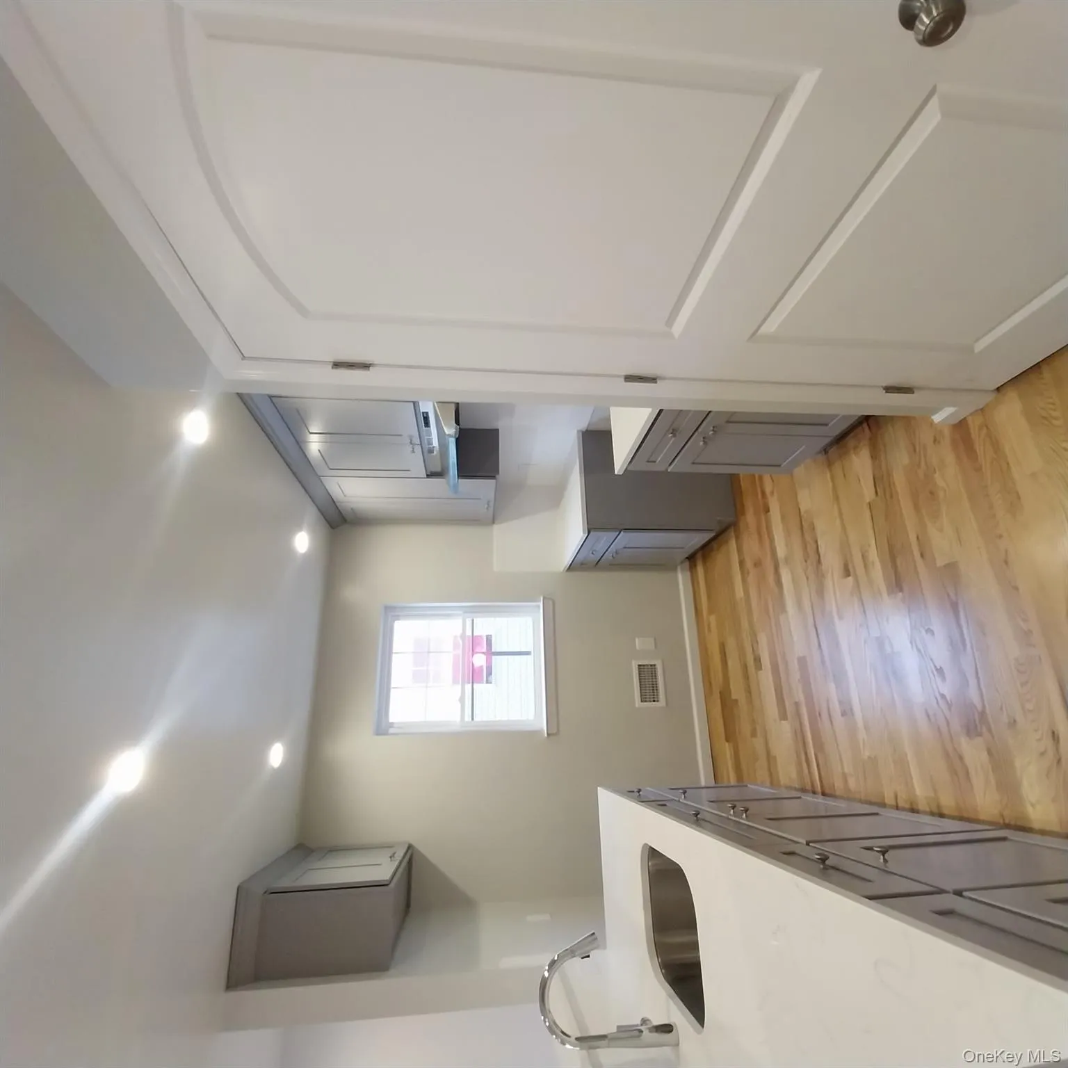 Kitchen with gray cabinets, light wood finished floors, light stone counters, recessed lighting, and exhaust hood Kitchen with gray cabinets, light wood finished floors, light stone counters, recessed lighting, and exhaust hood