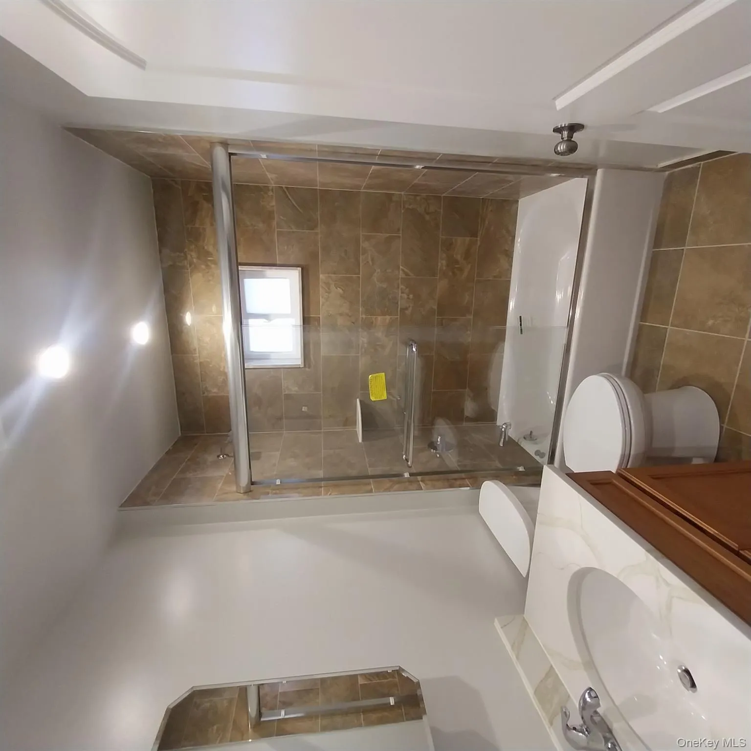 Bathroom with shower / bath combination with glass door, vanity, and light tile patterned flooring Bathroom with shower / bath combination with glass door, vanity, and light tile patterned flooring