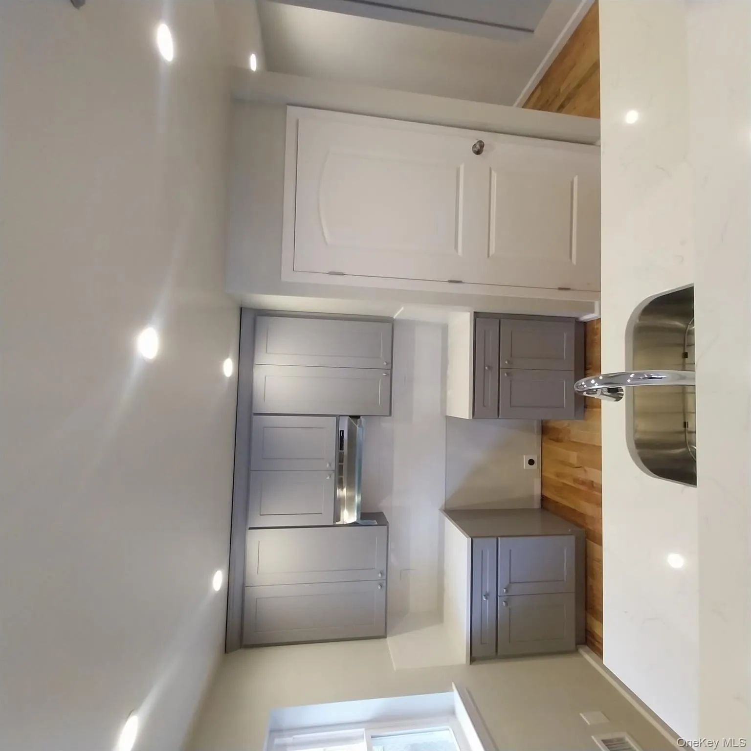 Kitchen with gray cabinets, light wood-style flooring, recessed lighting, light stone counters, and extractor fan Kitchen with gray cabinets, light wood-style flooring, recessed lighting, light stone counters, and extractor fan