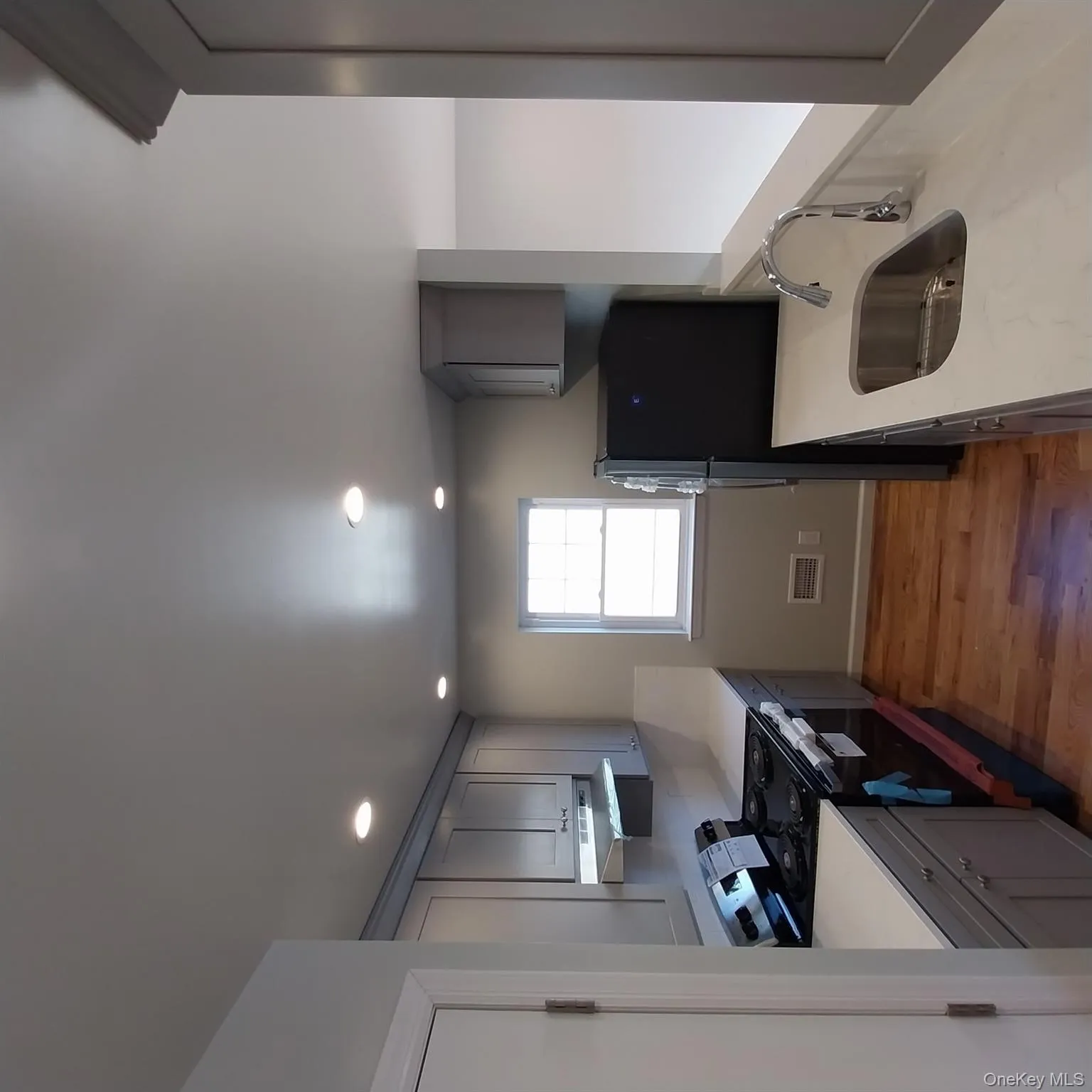 Kitchen with gray cabinetry, range, fridge, light stone countertops, and light wood finished floors Kitchen with gray cabinetry, range, fridge, light stone countertops, and light wood finished floors