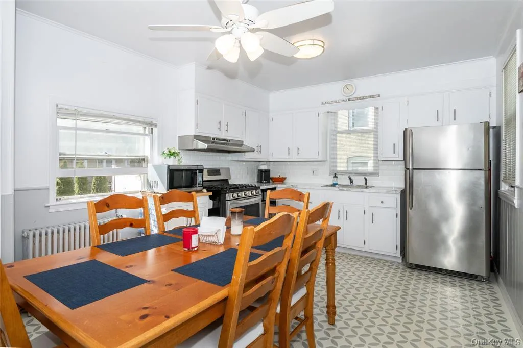 Kitchen featuring light flooring, stainless steel appliances, white cabinets, plenty of natural light, and ornamental molding Kitchen featuring light flooring, stainless steel appliances, white cabinets, plenty of natural light, and ornamental molding