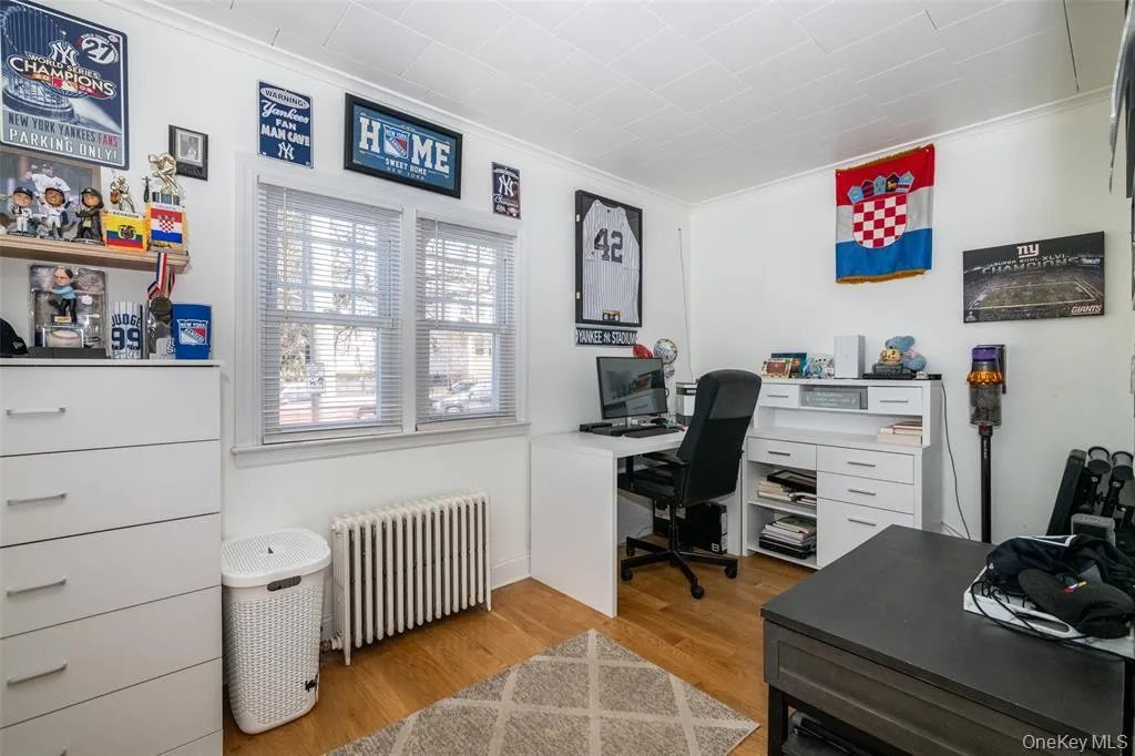 Home office with radiator, light wood-type flooring, and crown molding Home office with radiator, light wood-type flooring, and crown molding