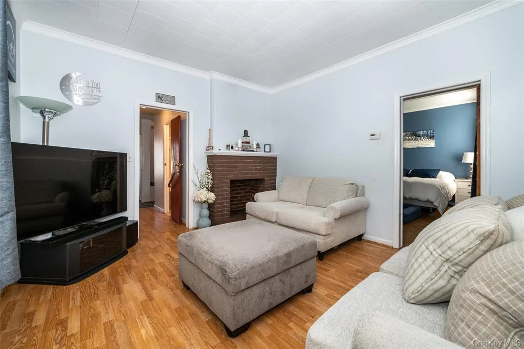 Living room with ornamental molding, wood finished floors, and a brick fireplace Living room with ornamental molding, wood finished floors, and a brick fireplace