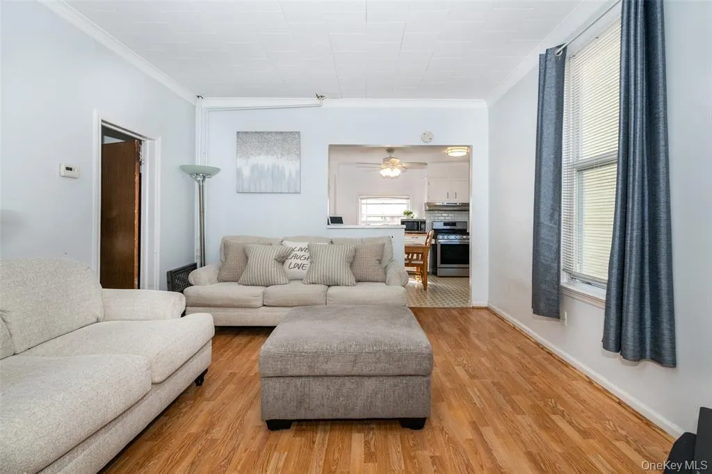Living area with crown molding, wood finished floors, and a ceiling fan Living area with crown molding, wood finished floors, and a ceiling fan