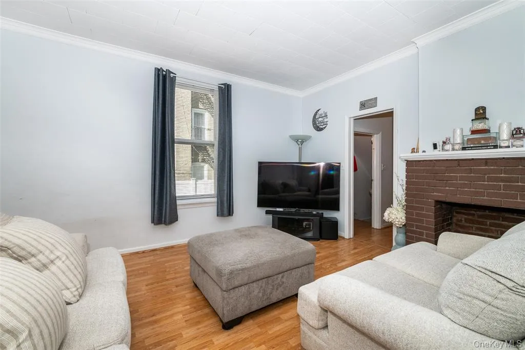 Living room with crown molding, a brick fireplace, and wood finished floors Living room with crown molding, a brick fireplace, and wood finished floors