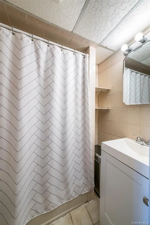 Bathroom with tile walls, vanity, and a shower with shower curtain Bathroom with tile walls, vanity, and a shower with shower curtain