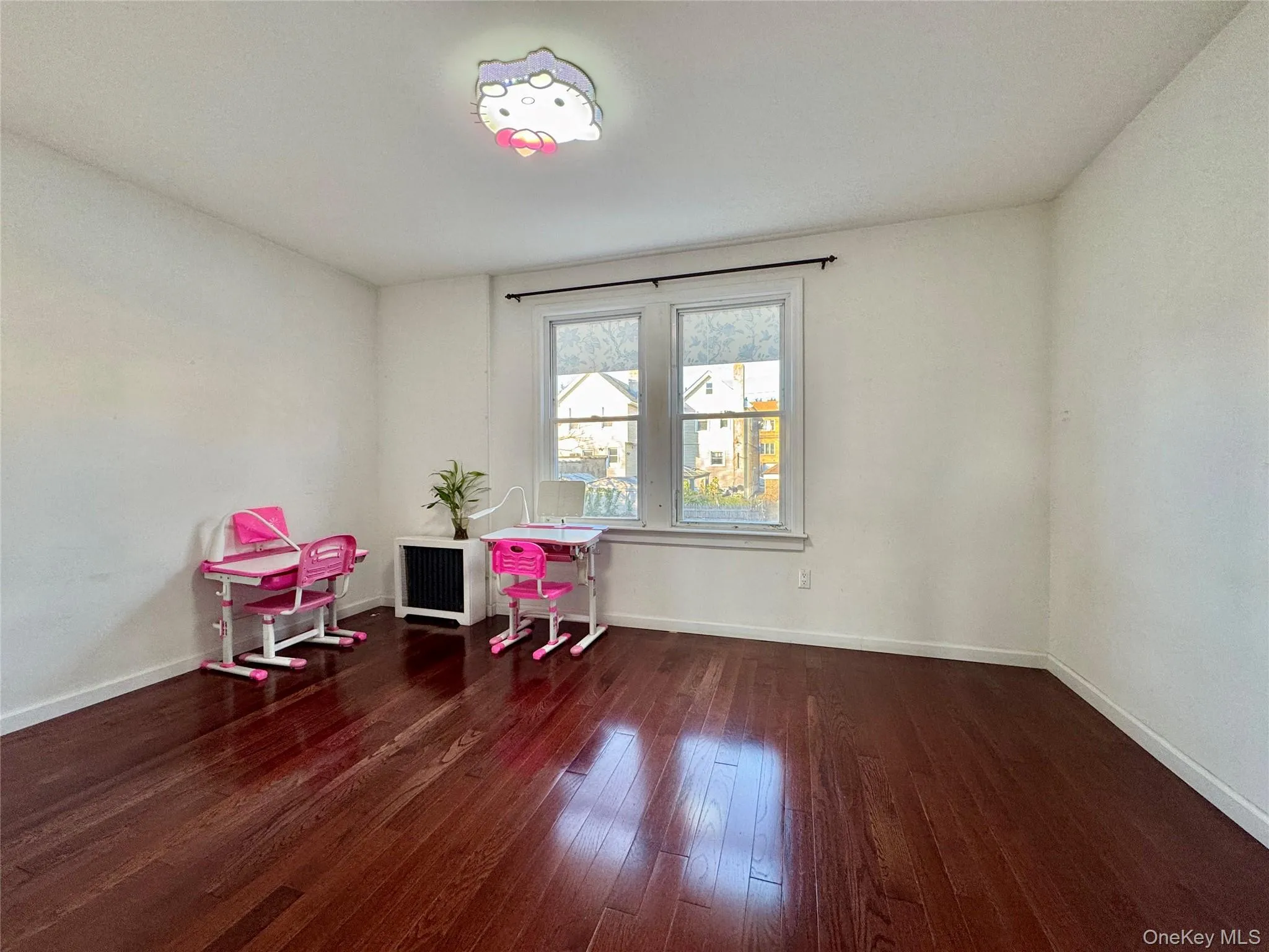 Recreation room featuring dark wood finished floors and radiator Recreation room featuring dark wood finished floors and radiator