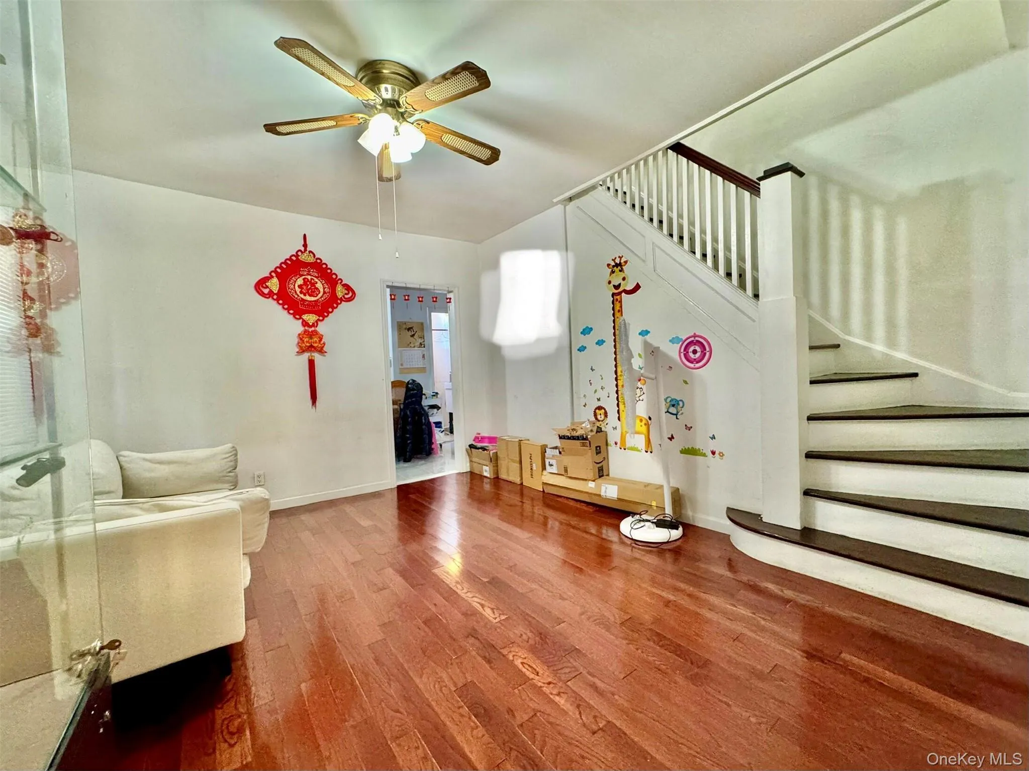 Living room featuring stairs, hardwood / wood-style floors, and ceiling fan Living room featuring stairs, hardwood / wood-style floors, and ceiling fan