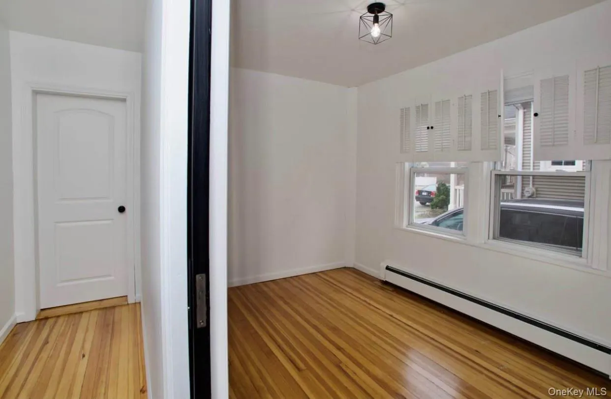 Spare room with a baseboard heating unit and light wood-type flooring Spare room with a baseboard heating unit and light wood-type flooring