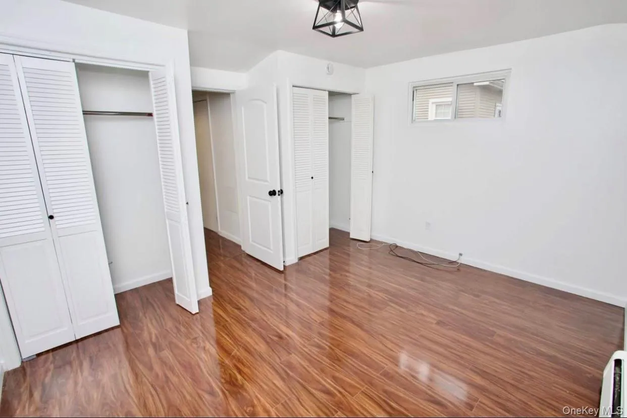 Unfurnished bedroom featuring two closets and dark wood finished floors Unfurnished bedroom featuring two closets and dark wood finished floors