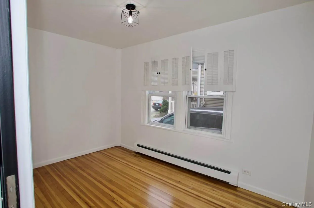 Unfurnished room featuring baseboard heating and light wood-style flooring Unfurnished room featuring baseboard heating and light wood-style flooring