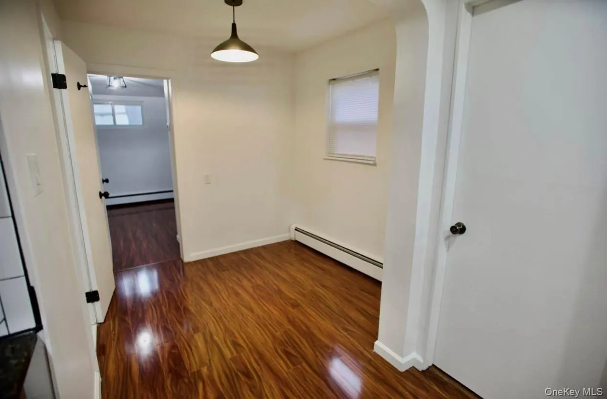 Hall featuring baseboard heating, dark wood-style floors, and arched walkways Hall featuring baseboard heating, dark wood-style floors, and arched walkways