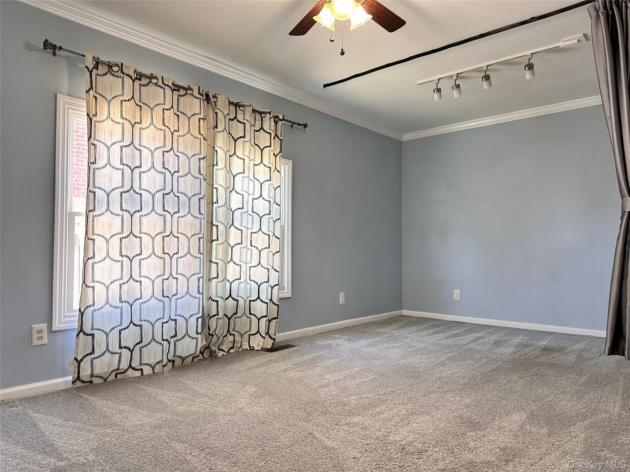 Unfurnished room with ornamental molding, rail lighting, light colored carpet, and ceiling fan Unfurnished room with ornamental molding, rail lighting, light colored carpet, and ceiling fan