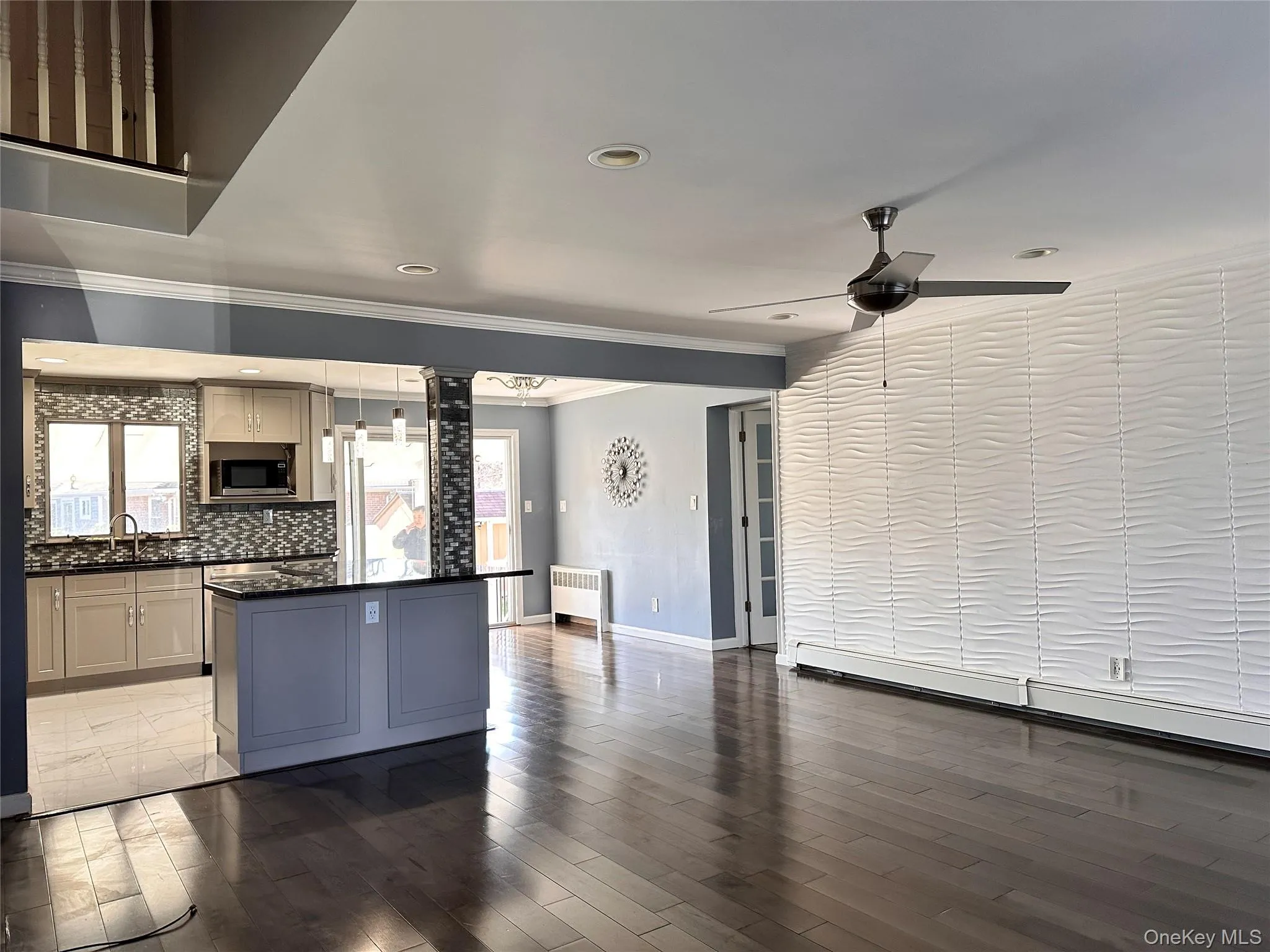 Kitchen featuring dark wood-style floors, open floor plan, crown molding, a kitchen island, and stainless steel microwave Kitchen featuring dark wood-style floors, open floor plan, crown molding, a kitchen island, and stainless steel microwave