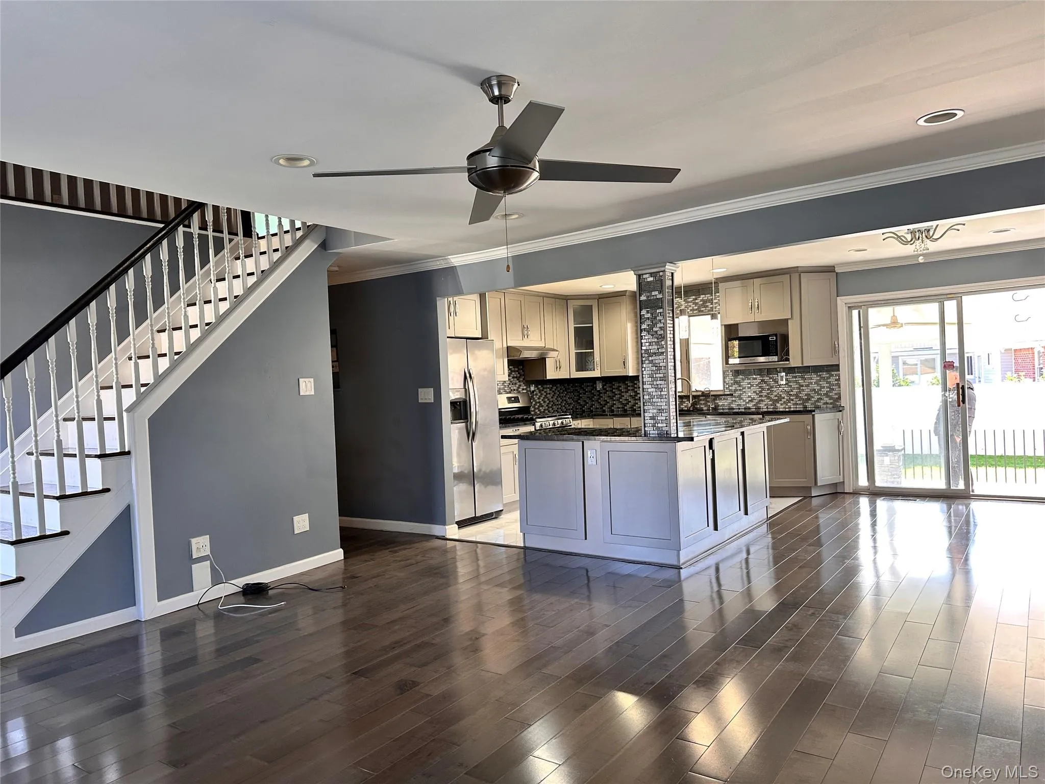 Kitchen with ceiling fan, dark wood-style floors, ornamental molding, stainless steel appliances, and a kitchen island Kitchen with ceiling fan, dark wood-style floors, ornamental molding, stainless steel appliances, and a kitchen island