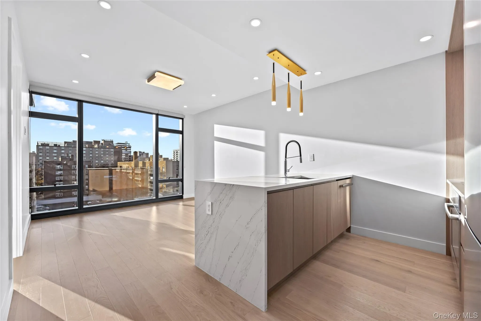 Kitchen featuring modern cabinets, a view of city, light stone counters, a peninsula, and a wall of windows Kitchen featuring modern cabinets, a view of city, light stone counters, a peninsula, and a wall of windows