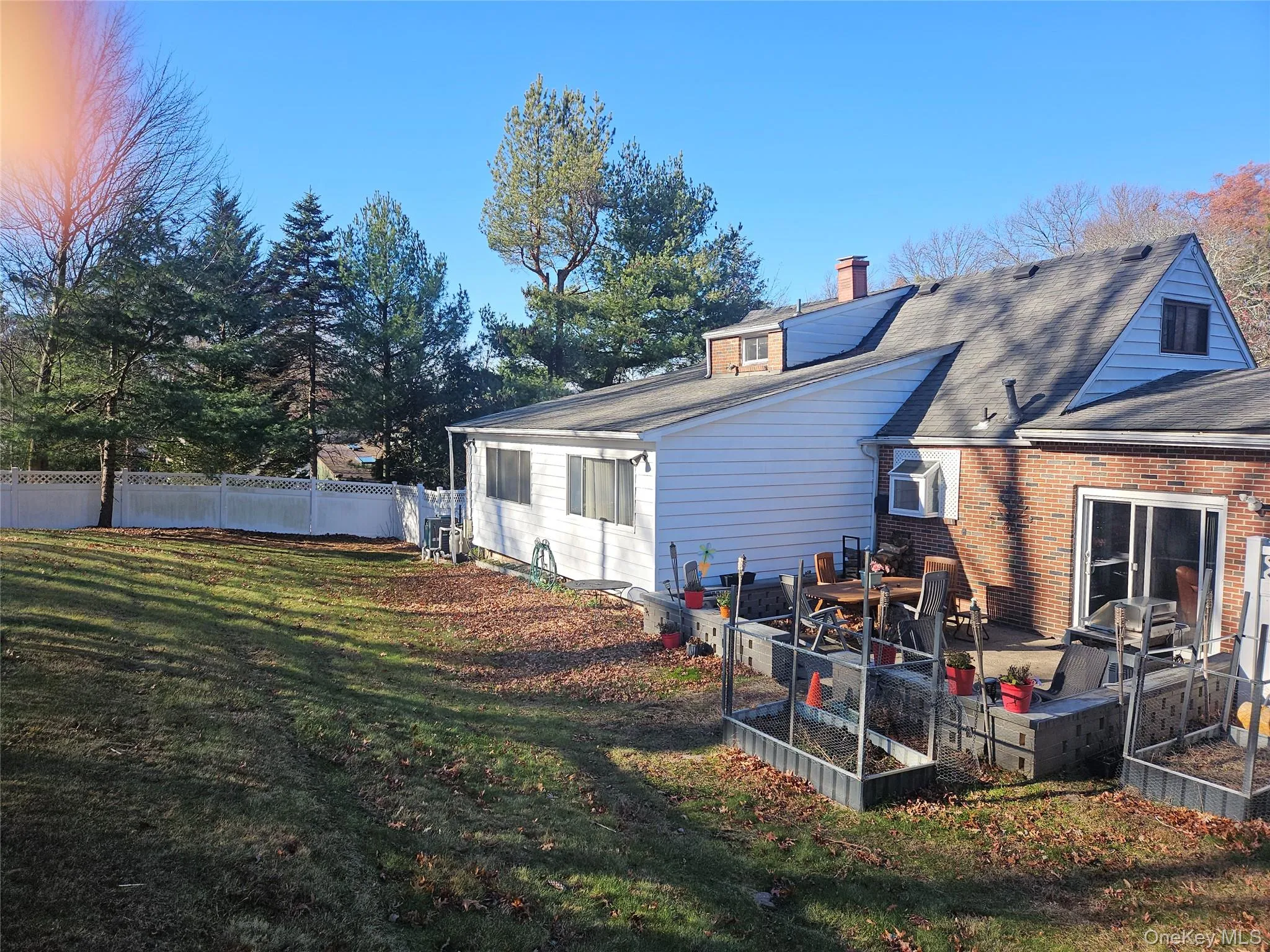 Rear view of house featuring a garden, a chimney, and brick siding Rear view of house featuring a garden, a chimney, and brick siding