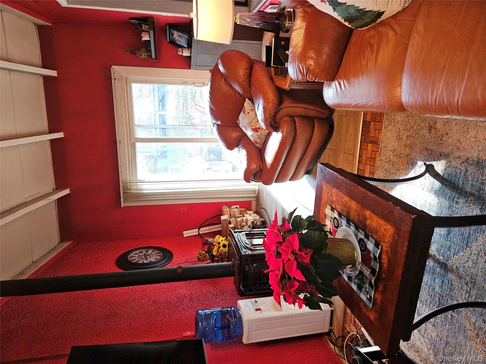 Living area with a wood stove, beamed ceiling, and a textured wall Living area with a wood stove, beamed ceiling, and a textured wall