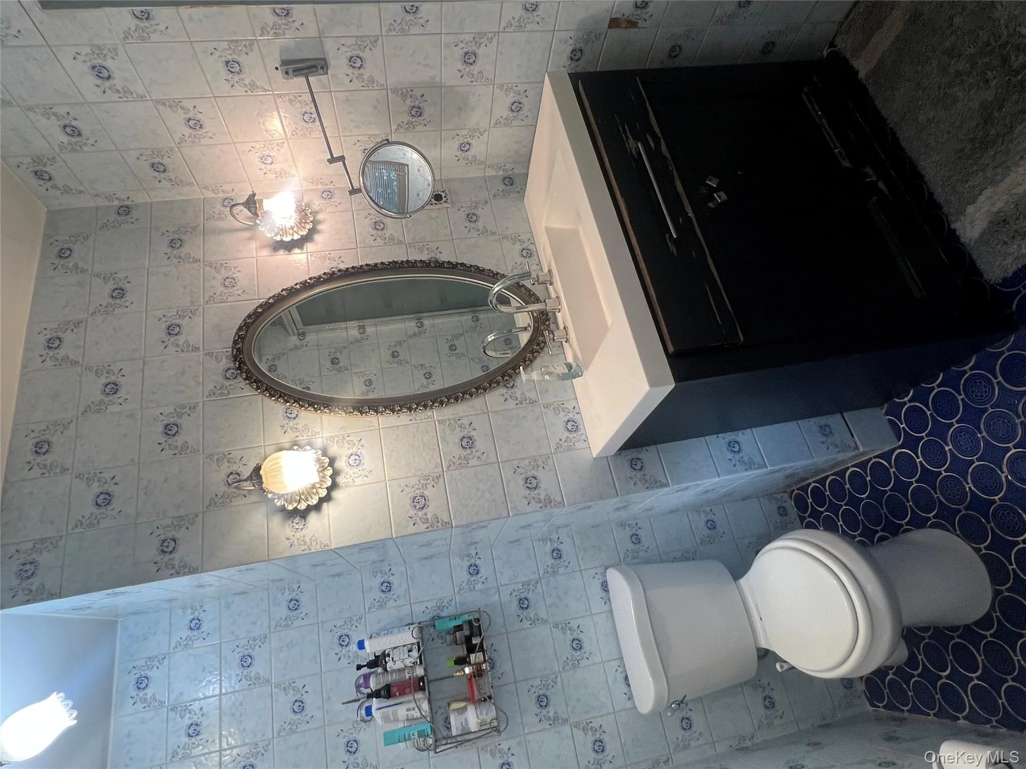 Bathroom with tile walls, vanity, dark tile patterned flooring, and a shower Bathroom with tile walls, vanity, dark tile patterned flooring, and a shower