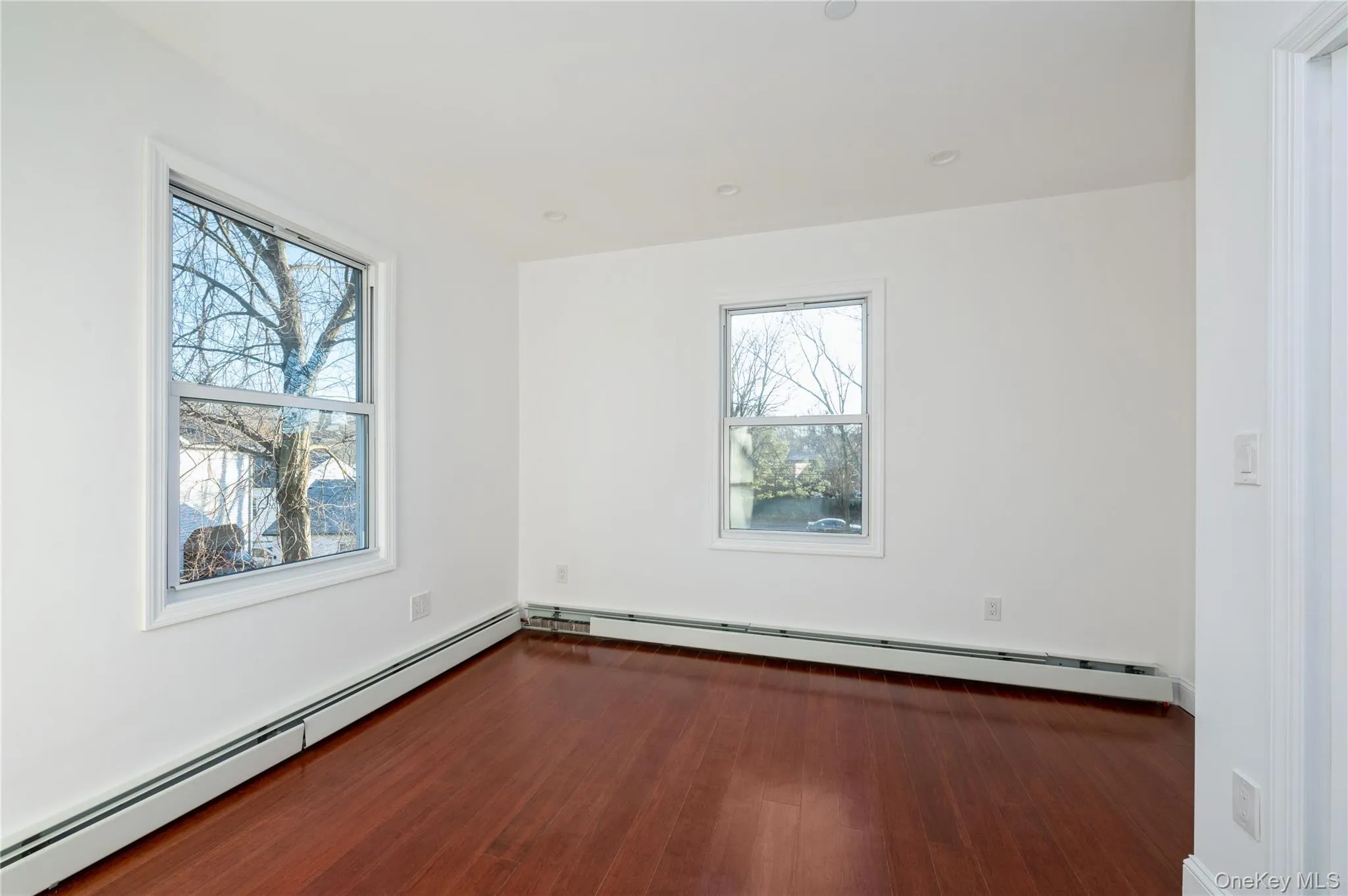 Spare room with a baseboard radiator, dark wood-type flooring, and recessed lighting Spare room with a baseboard radiator, dark wood-type flooring, and recessed lighting