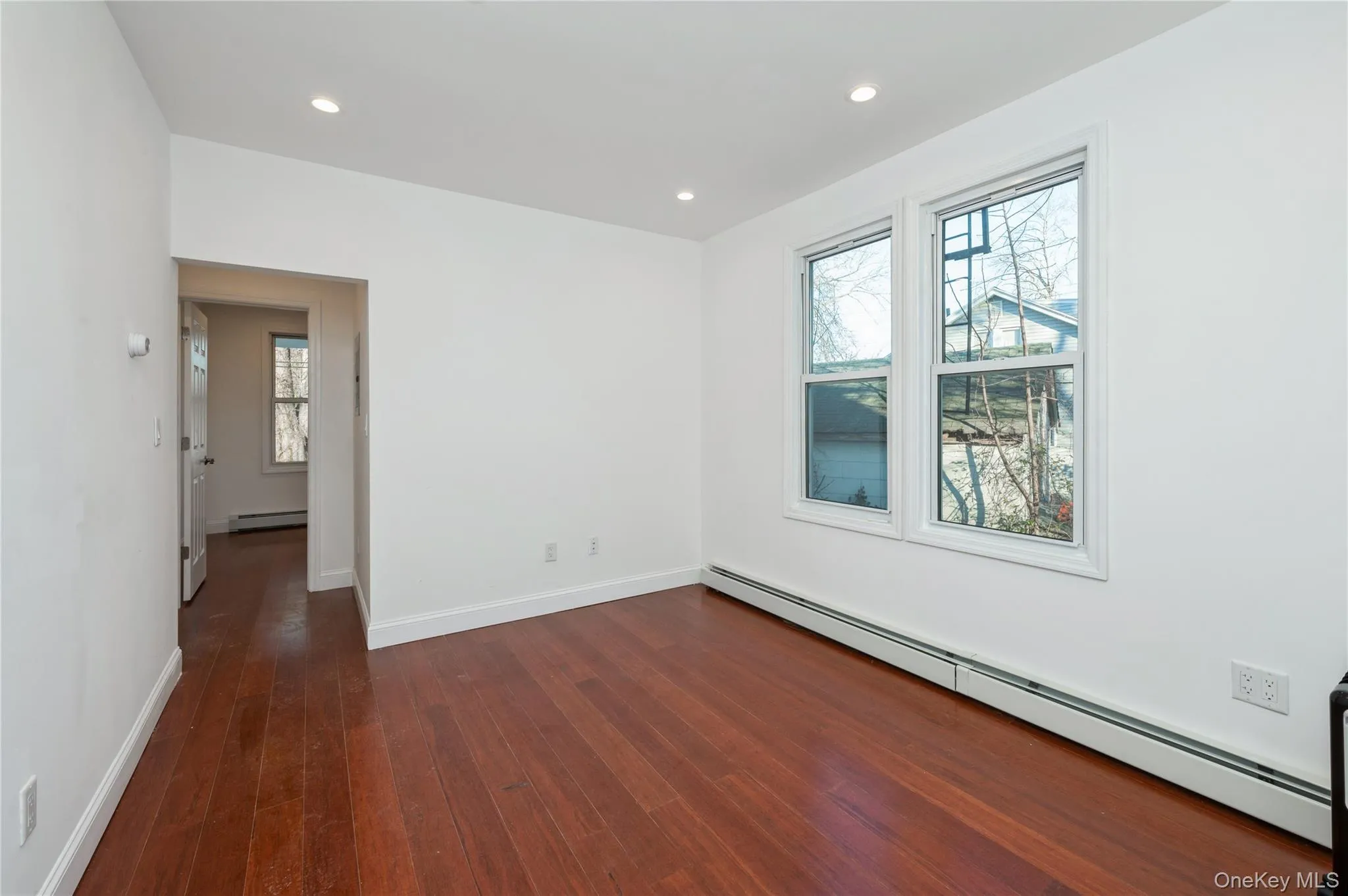 Unfurnished room with a baseboard heating unit, dark wood-style flooring, and recessed lighting Unfurnished room with a baseboard heating unit, dark wood-style flooring, and recessed lighting