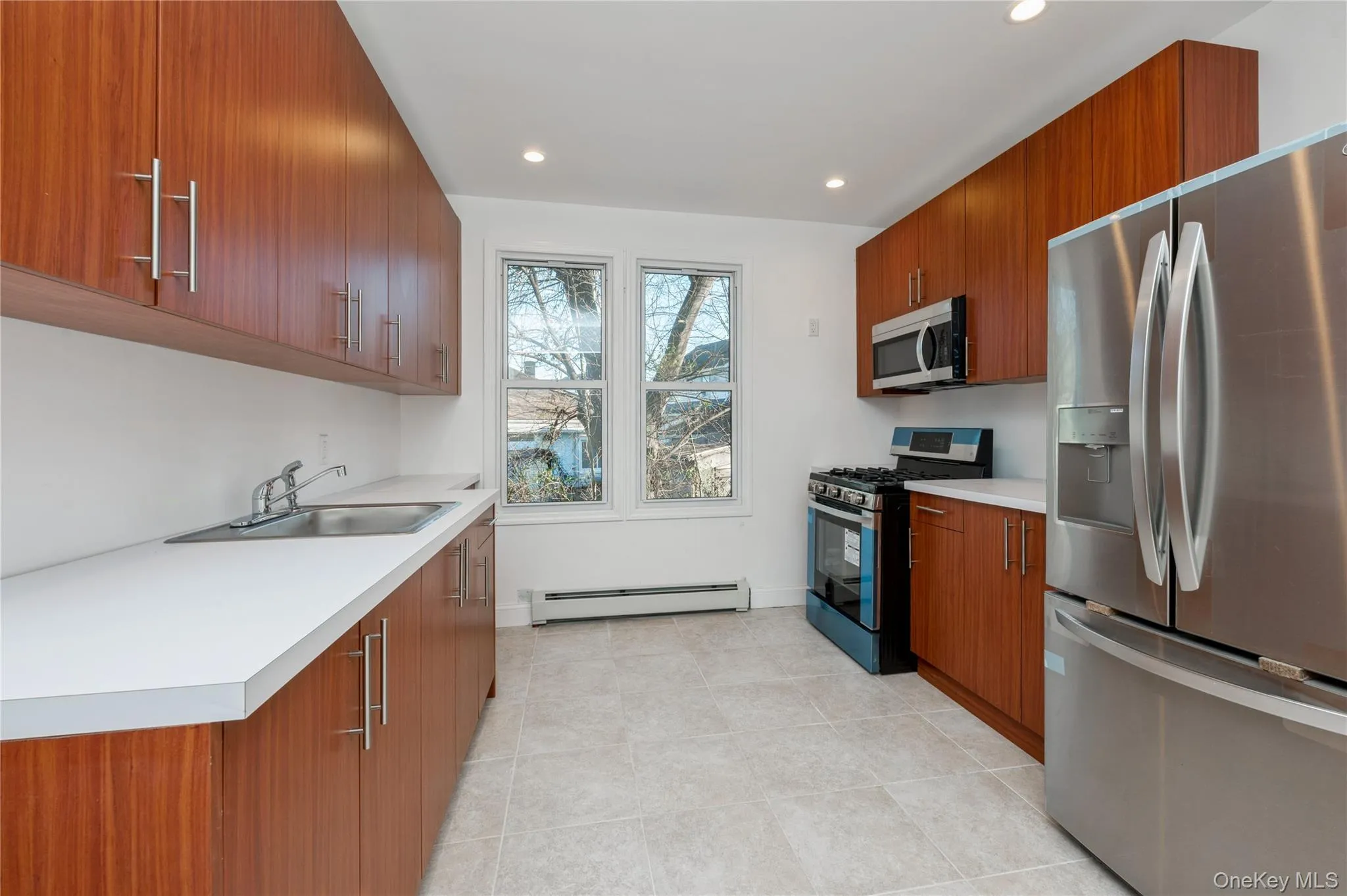 Kitchen with appliances with stainless steel finishes, brown cabinetry, modern cabinets, light countertops, and recessed lighting Kitchen with appliances with stainless steel finishes, brown cabinetry, modern cabinets, light countertops, and recessed lighting
