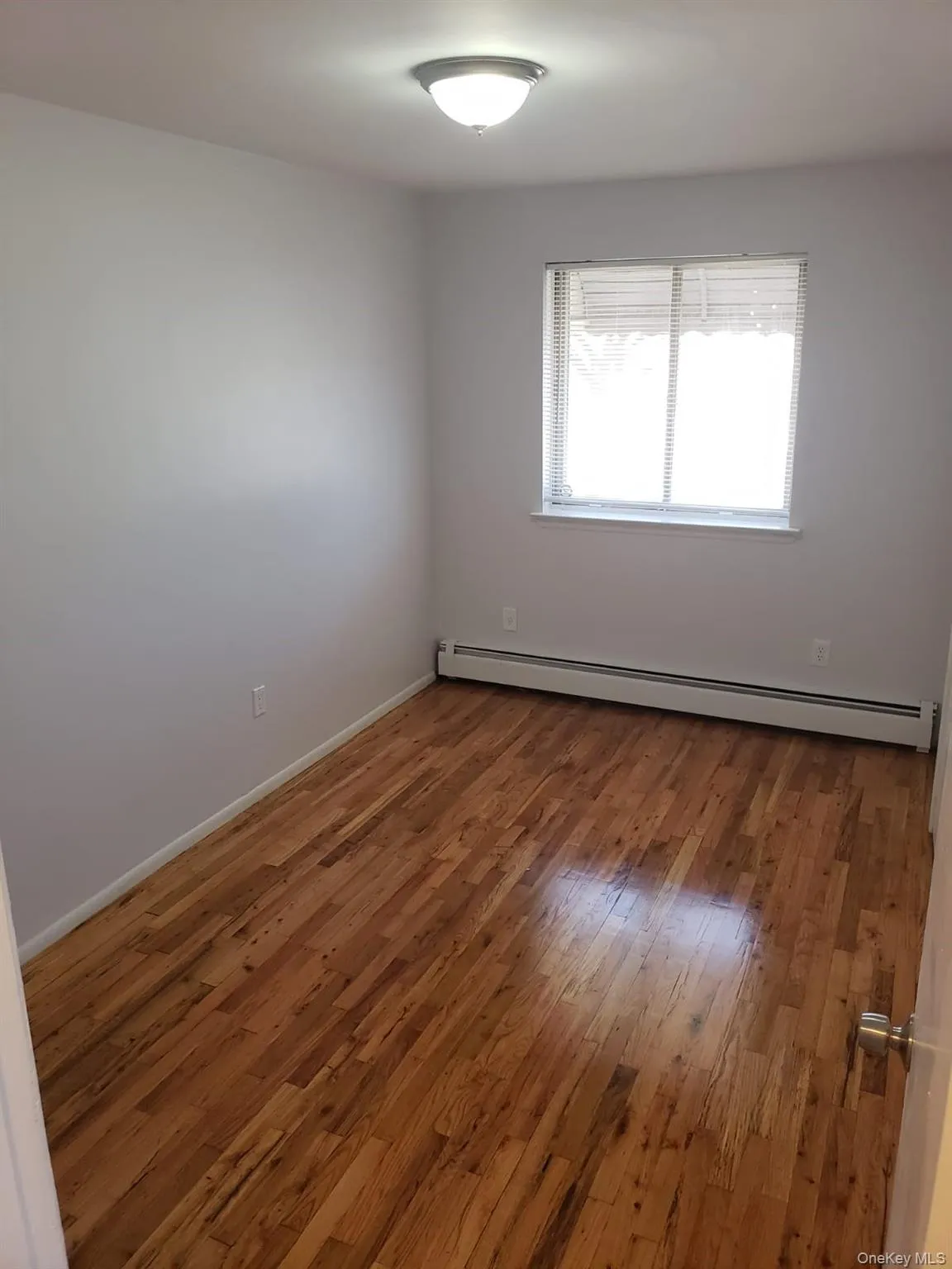 Unfurnished room featuring a baseboard heating unit and hardwood / wood-style flooring Unfurnished room featuring a baseboard heating unit and hardwood / wood-style flooring