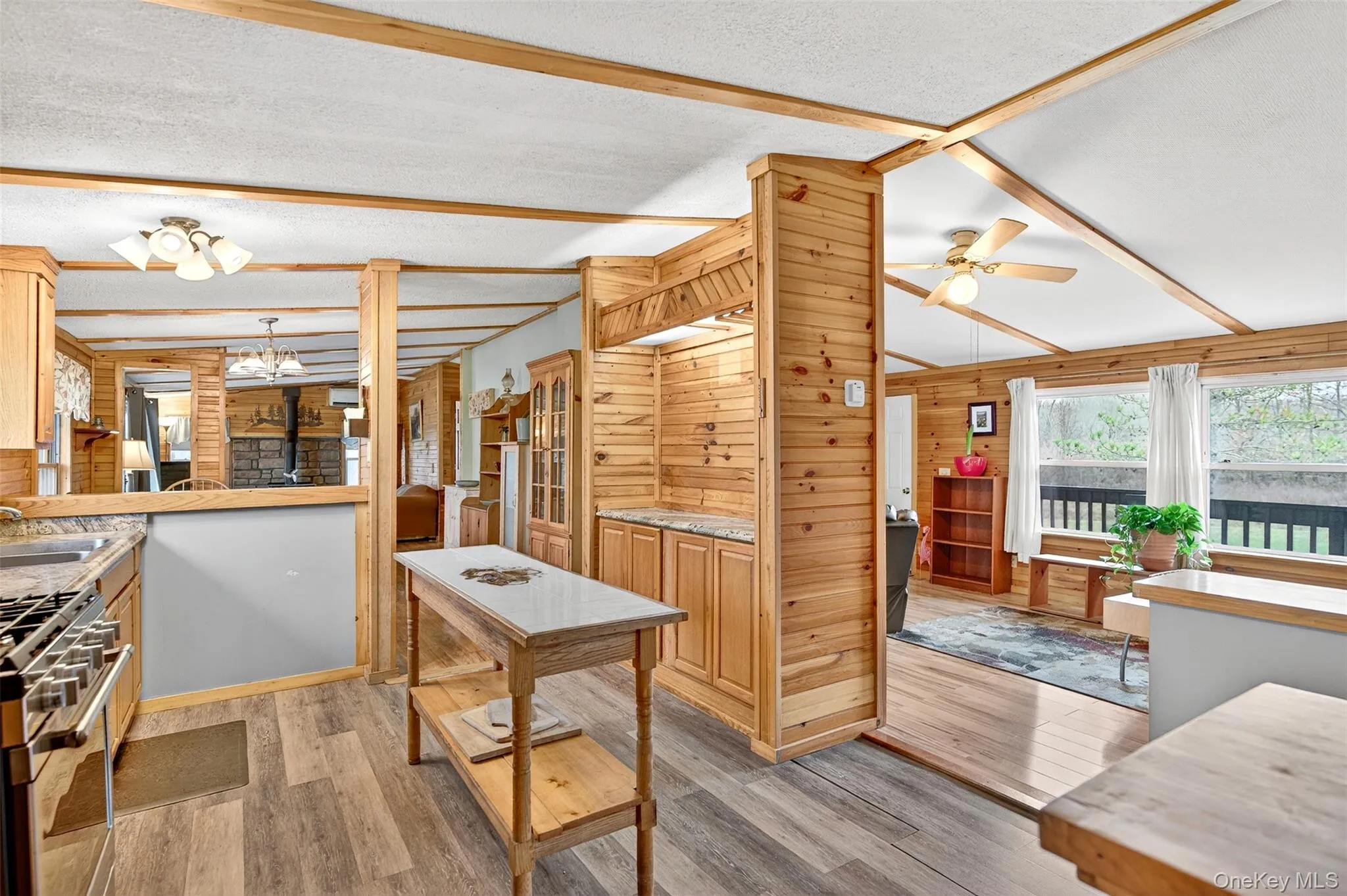 Kitchen featuring light wood-style floors, stainless steel range with gas cooktop, wooden walls, light countertops, and a ceiling fan Kitchen featuring light wood-style floors, stainless steel range with gas cooktop, wooden walls, light countertops, and a ceiling fan