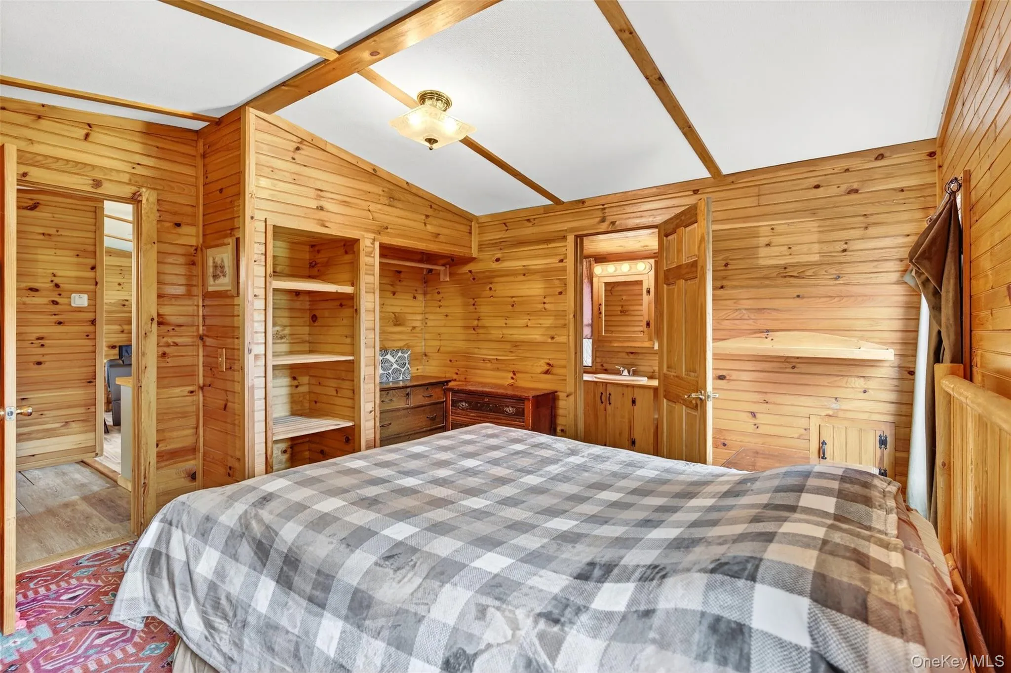 Bedroom featuring vaulted ceiling and wood walls Bedroom featuring vaulted ceiling and wood walls