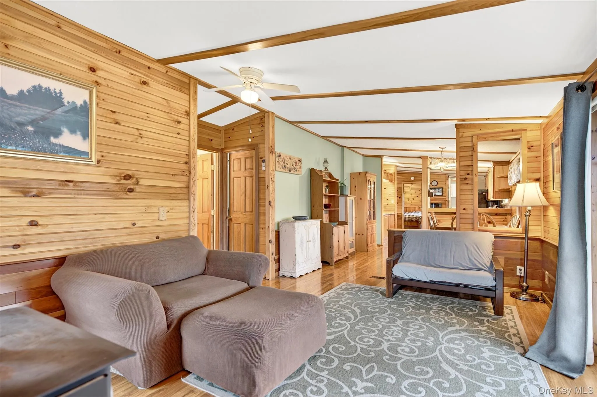 Bedroom with wood walls, a ceiling fan, light wood finished floors, and beamed ceiling Bedroom with wood walls, a ceiling fan, light wood finished floors, and beamed ceiling