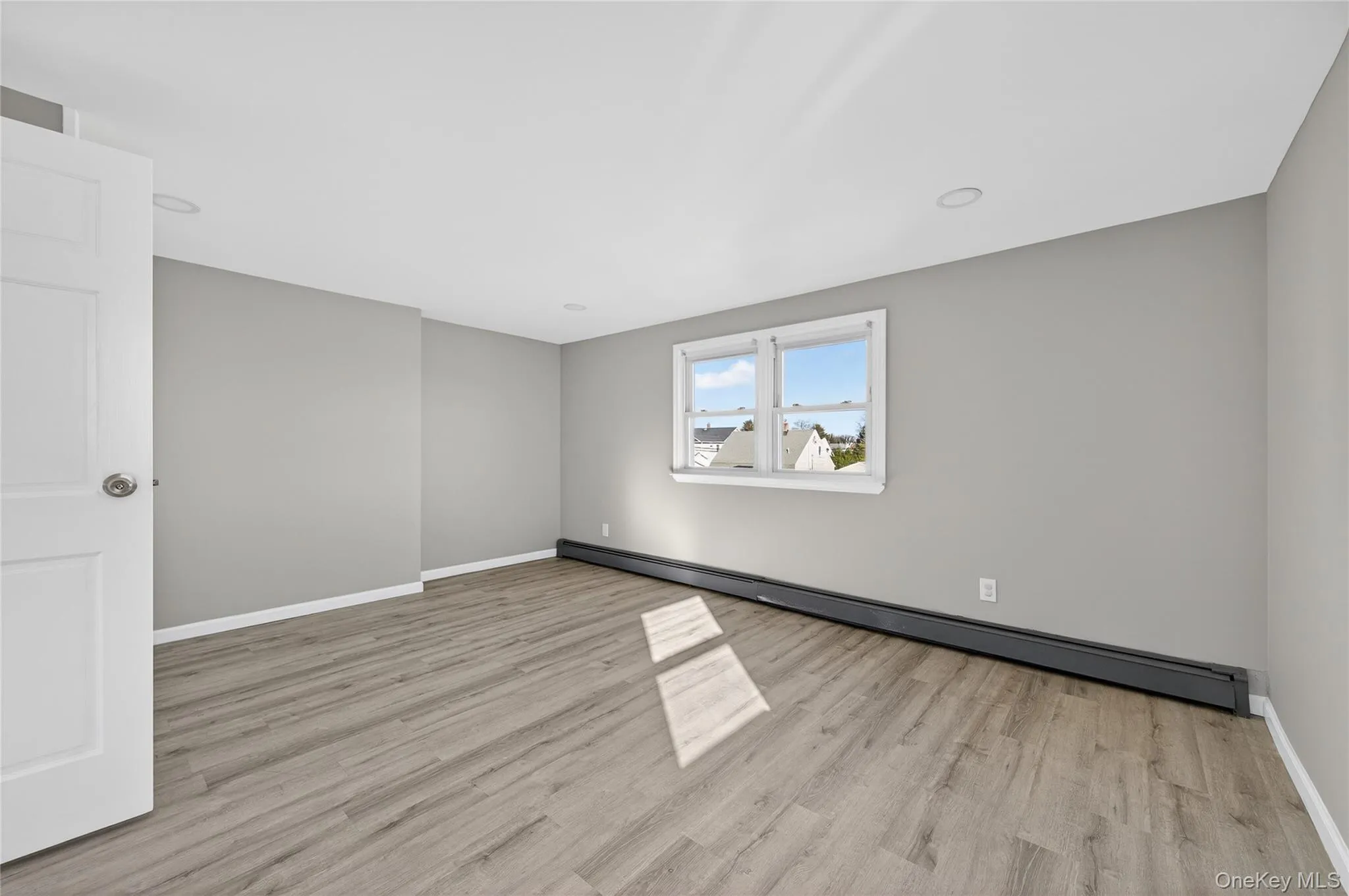 Spare room featuring a baseboard radiator and light wood-style floors Spare room featuring a baseboard radiator and light wood-style floors