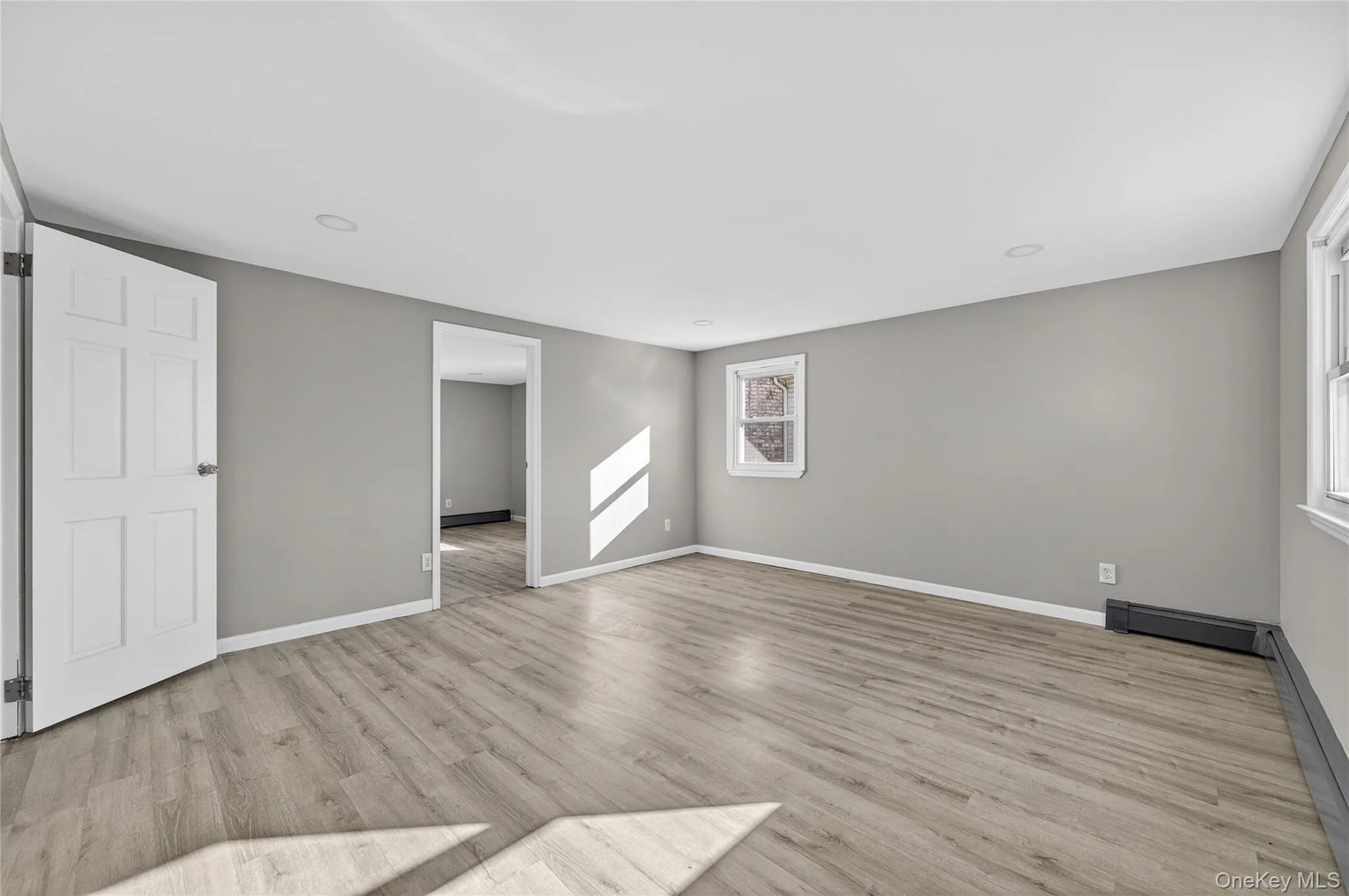 Unfurnished room featuring light wood-style flooring, baseboard heating, and a baseboard radiator Unfurnished room featuring light wood-style flooring, baseboard heating, and a baseboard radiator