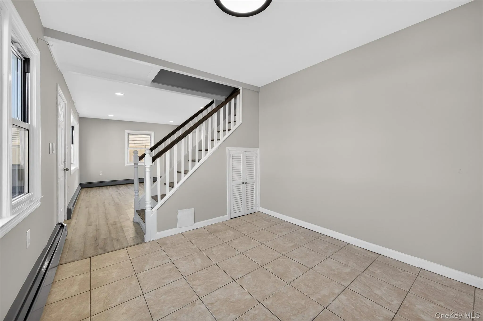 Foyer with a baseboard heating unit, light tile patterned floors, stairs, recessed lighting, and baseboard heating Foyer with a baseboard heating unit, light tile patterned floors, stairs, recessed lighting, and baseboard heating