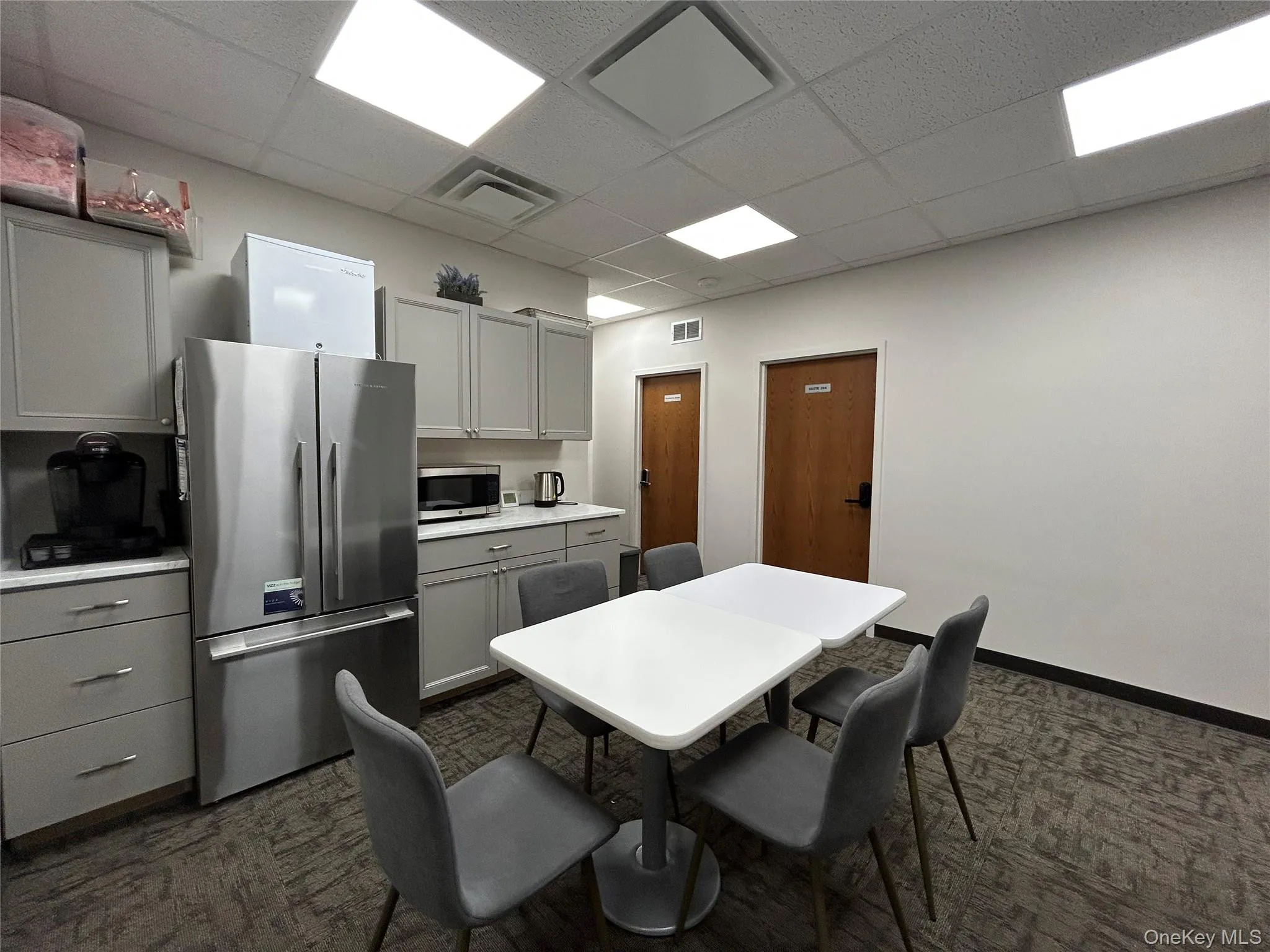 Kitchen featuring gray cabinetry, appliances with stainless steel finishes, a paneled ceiling, and light countertops Kitchen featuring gray cabinetry, appliances with stainless steel finishes, a paneled ceiling, and light countertops