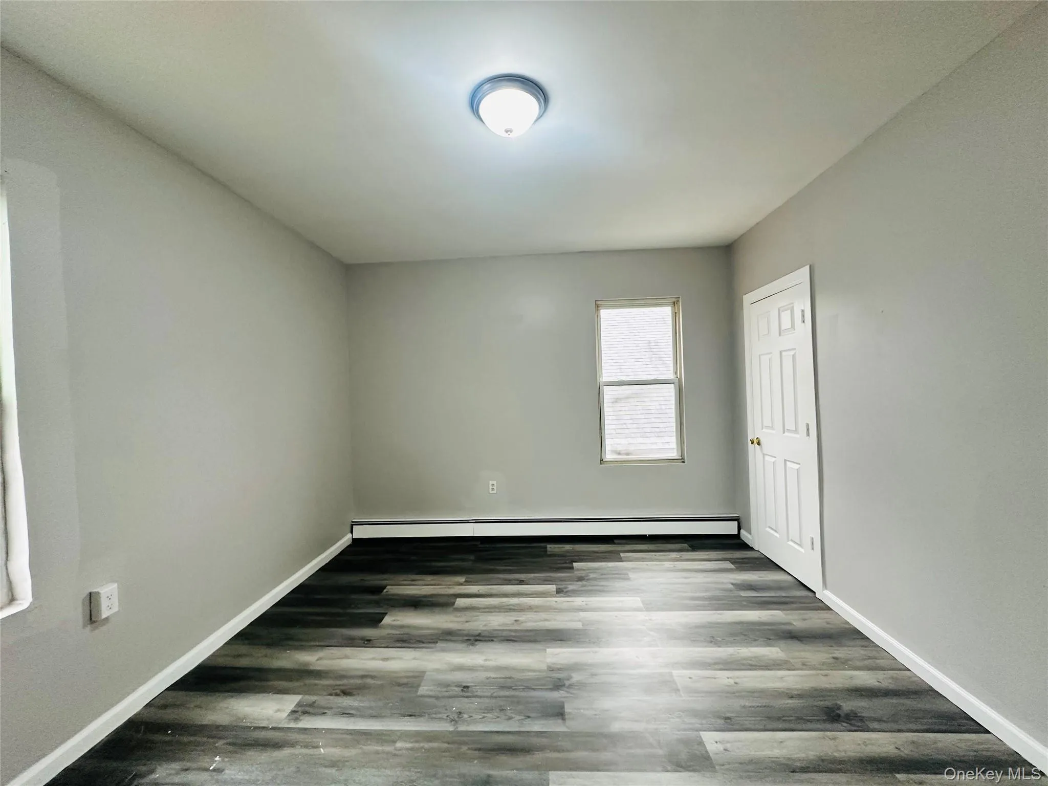Spare room with dark wood finished floors and baseboard heating Spare room with dark wood finished floors and baseboard heating