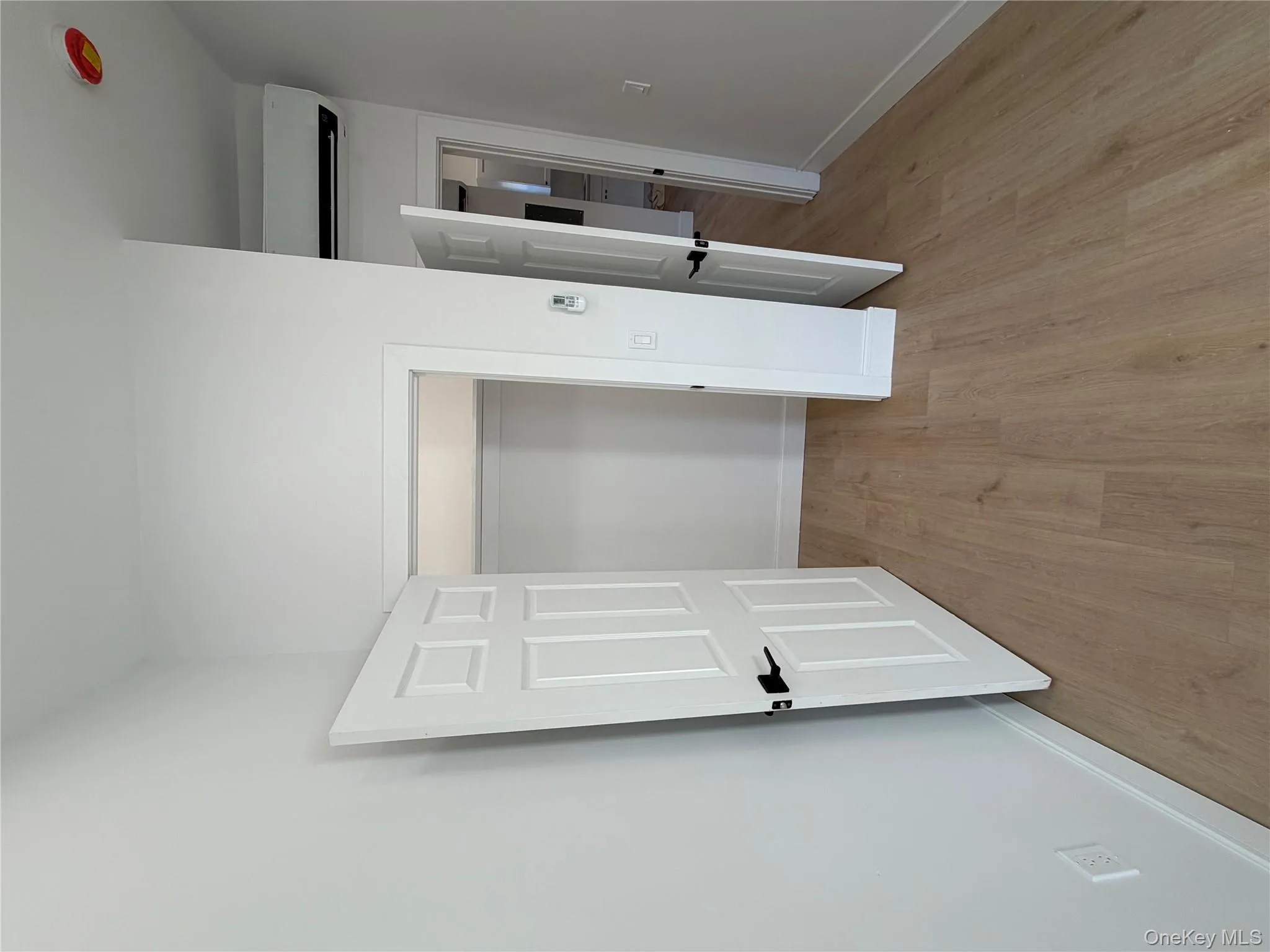 Unfurnished bedroom featuring light wood-style floors, a closet, and a wall mounted AC Unfurnished bedroom featuring light wood-style floors, a closet, and a wall mounted AC