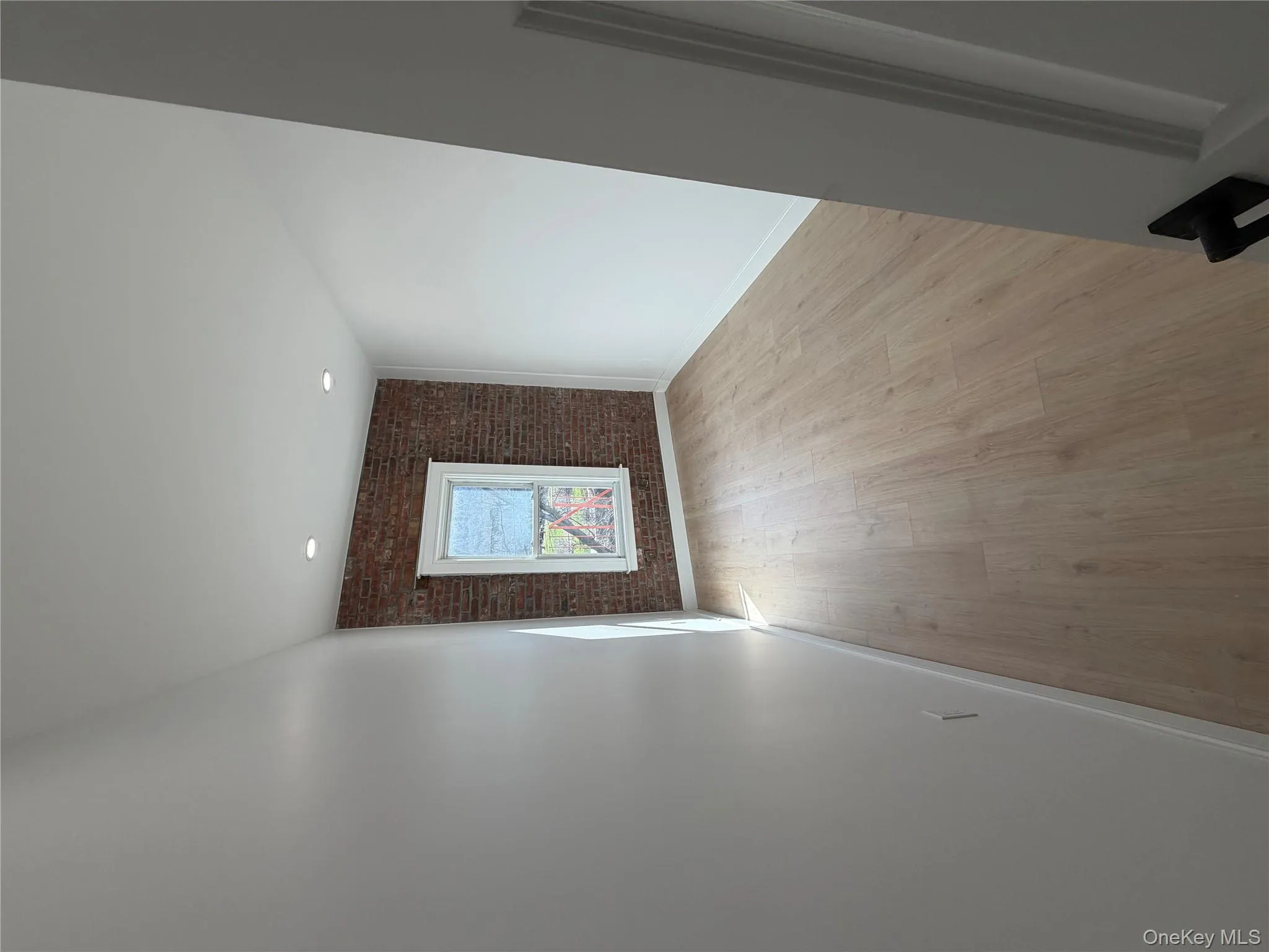 Unfurnished room featuring brick wall and light wood finished floors Unfurnished room featuring brick wall and light wood finished floors