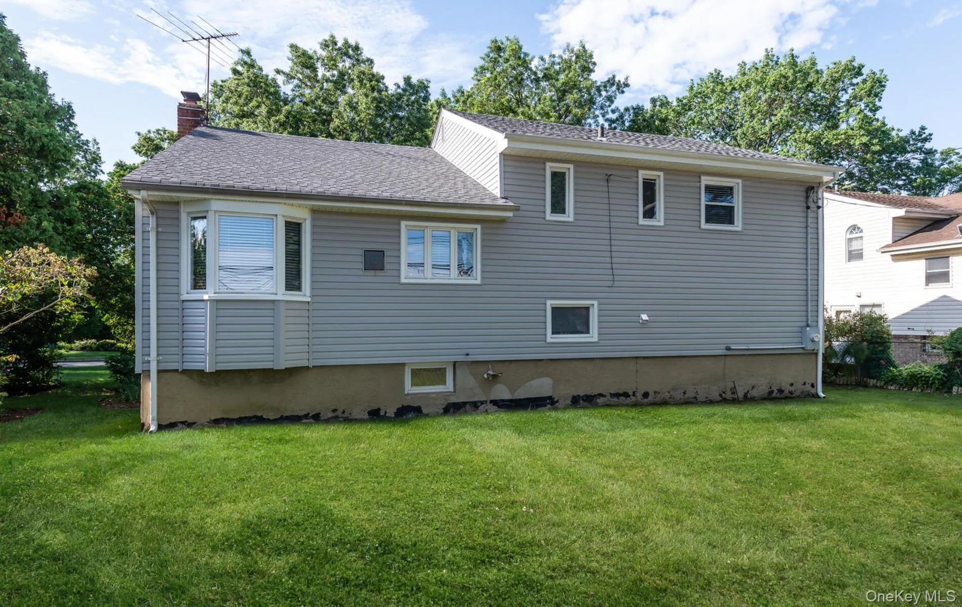 Back of property featuring a lawn, a chimney, and a shingled roof Back of property featuring a lawn, a chimney, and a shingled roof