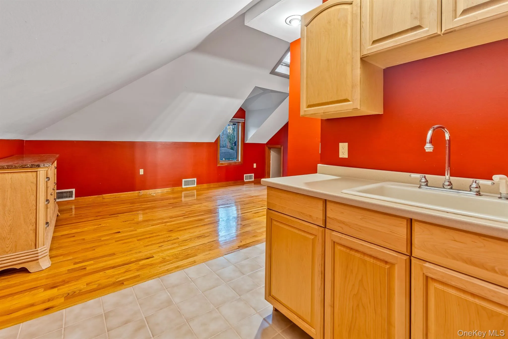 Kitchen featuring light brown cabinetry, light tile patterned floors, and lofted ceiling Kitchen featuring light brown cabinetry, light tile patterned floors, and lofted ceiling