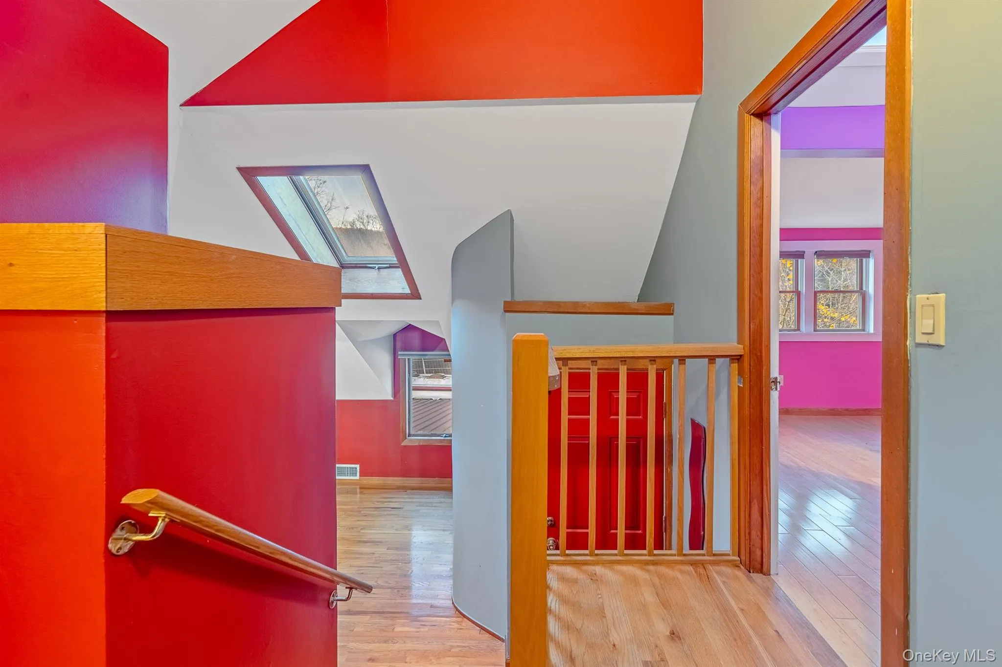 Hallway featuring light wood finished floors, an upstairs landing, and a skylight Hallway featuring light wood finished floors, an upstairs landing, and a skylight