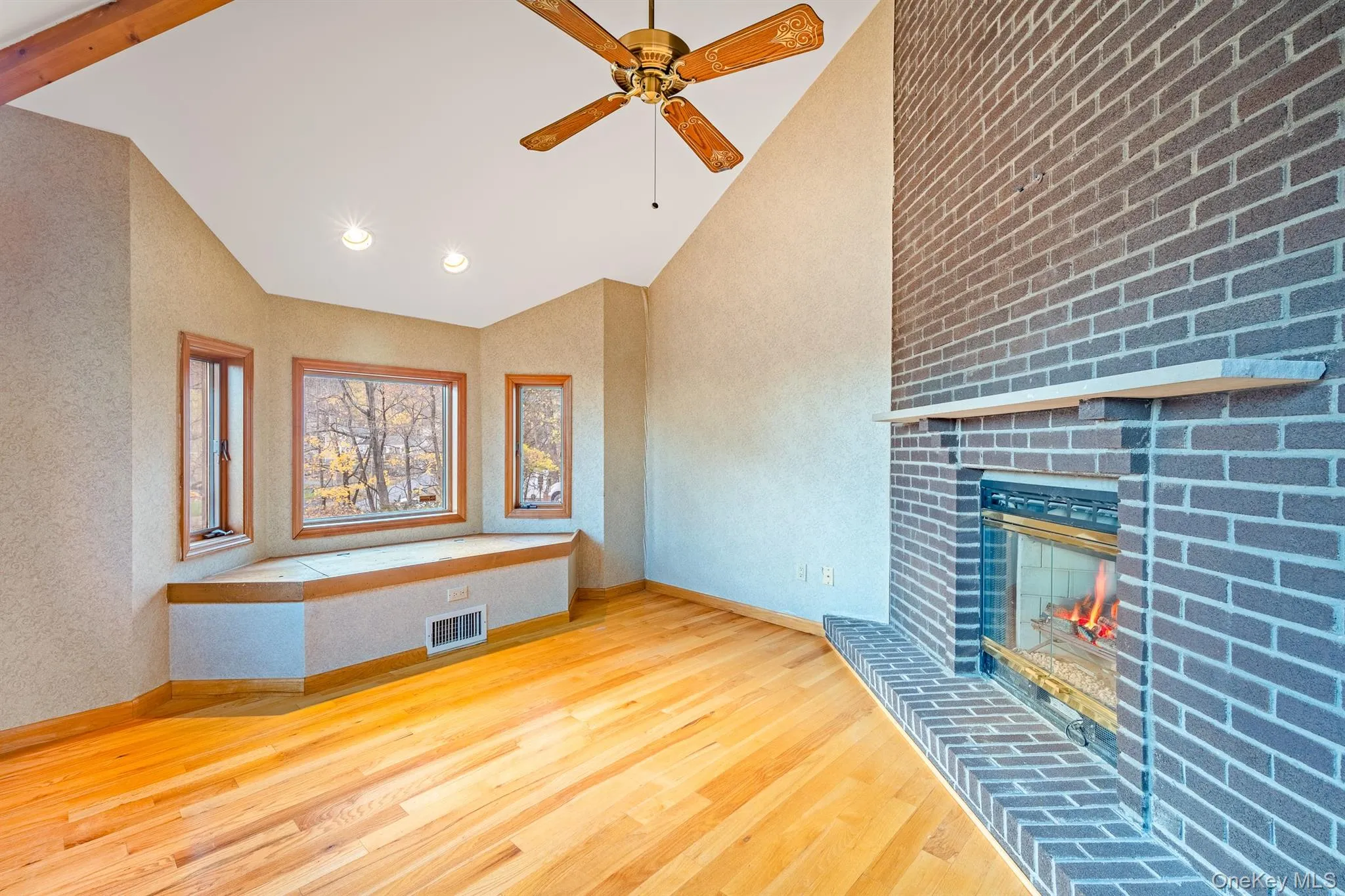 Unfurnished living room featuring light wood-style floors, a brick fireplace, high vaulted ceiling, a ceiling fan, and recessed lighting Unfurnished living room featuring light wood-style floors, a brick fireplace, high vaulted ceiling, a ceiling fan, and recessed lighting