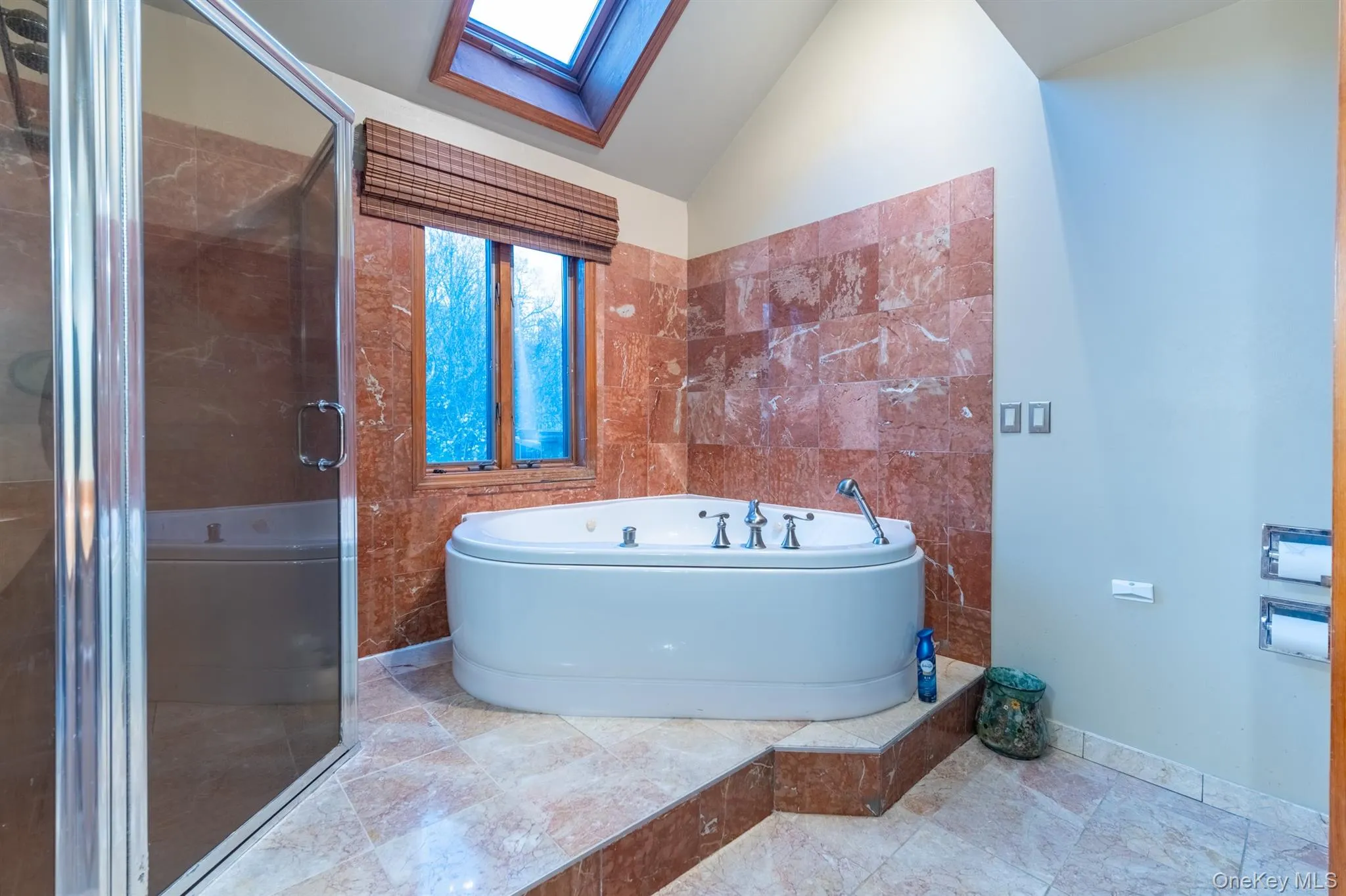 Full bath featuring a skylight, a garden tub, vaulted ceiling, a shower stall, and tile walls Full bath featuring a skylight, a garden tub, vaulted ceiling, a shower stall, and tile walls