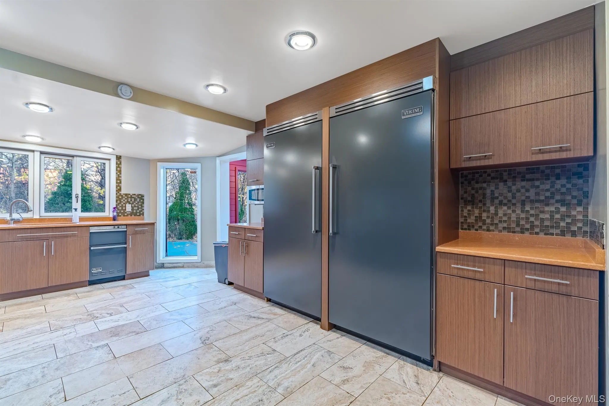 Kitchen featuring tasteful backsplash, built in fridge, brown cabinetry, and modern cabinets Kitchen featuring tasteful backsplash, built in fridge, brown cabinetry, and modern cabinets