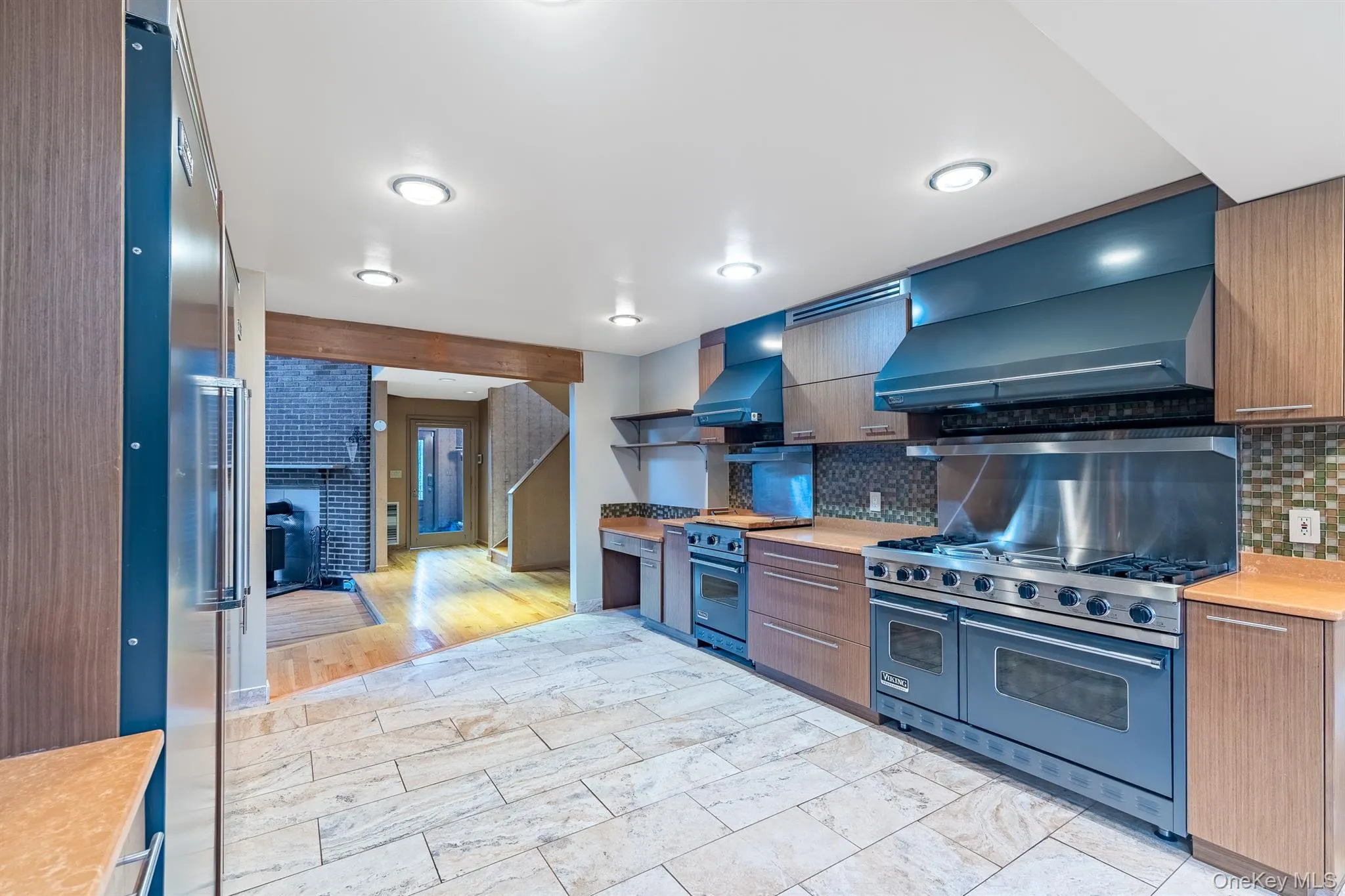 Kitchen featuring open shelves, light countertops, high quality appliances, and backsplash Kitchen featuring open shelves, light countertops, high quality appliances, and backsplash