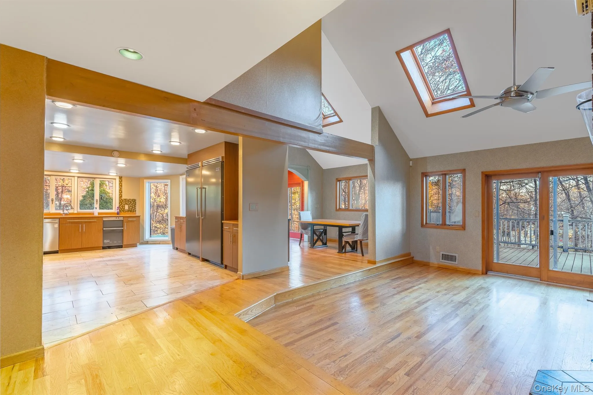 Unfurnished living room featuring light wood-type flooring, high vaulted ceiling, ceiling fan, and a skylight Unfurnished living room featuring light wood-type flooring, high vaulted ceiling, ceiling fan, and a skylight