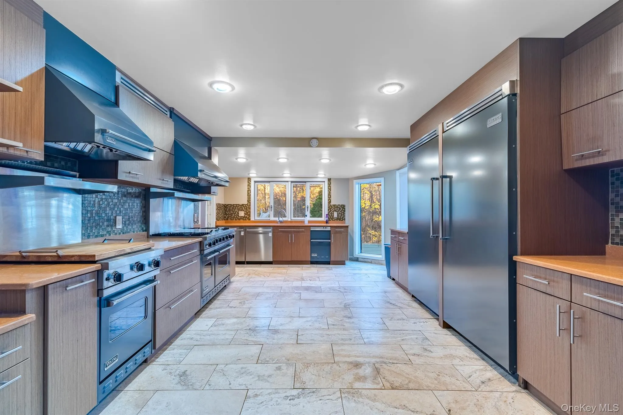 Kitchen with modern cabinets, decorative backsplash, ventilation hood, and high quality appliances Kitchen with modern cabinets, decorative backsplash, ventilation hood, and high quality appliances