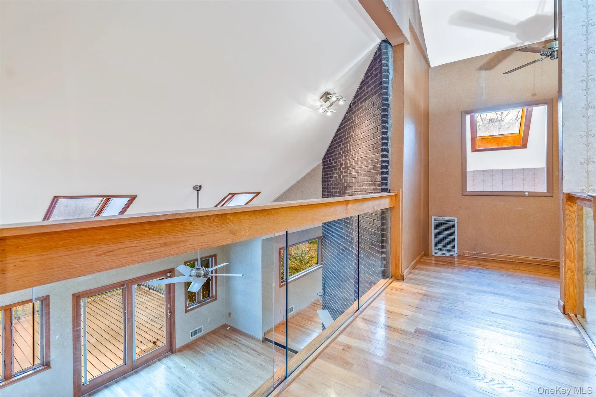 Hallway with healthy amount of natural light, a skylight, wood finished floors, high vaulted ceiling, and heating unit Hallway with healthy amount of natural light, a skylight, wood finished floors, high vaulted ceiling, and heating unit