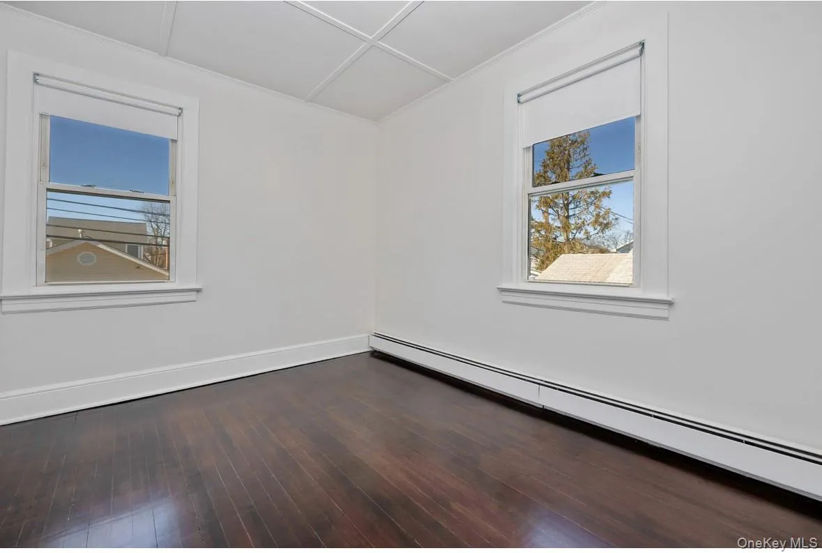 Spare room with a baseboard heating unit and dark wood-style floors Spare room with a baseboard heating unit and dark wood-style floors